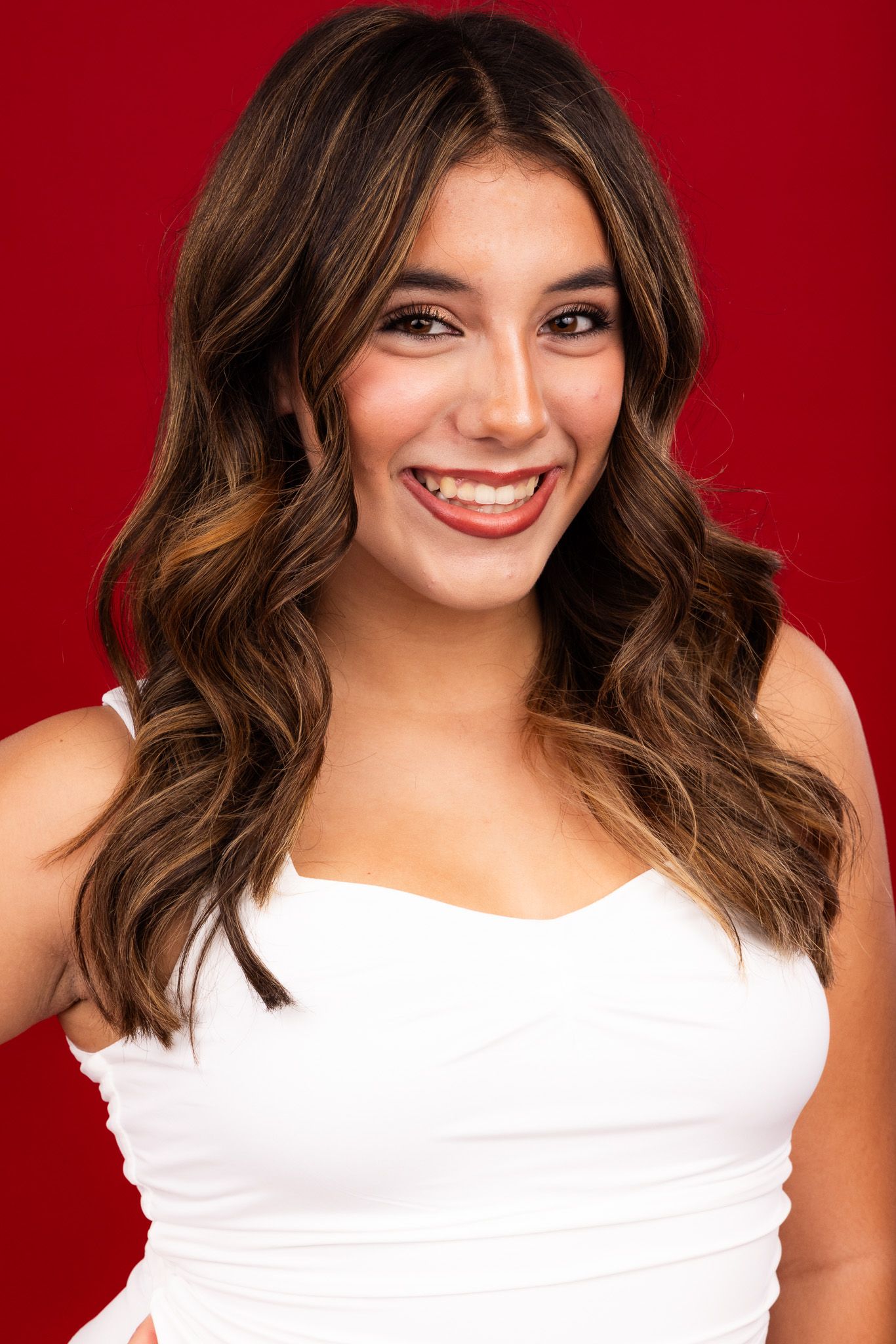 Portrait series against a red backdrop showing someone with wavy brown hair wearing a white top.