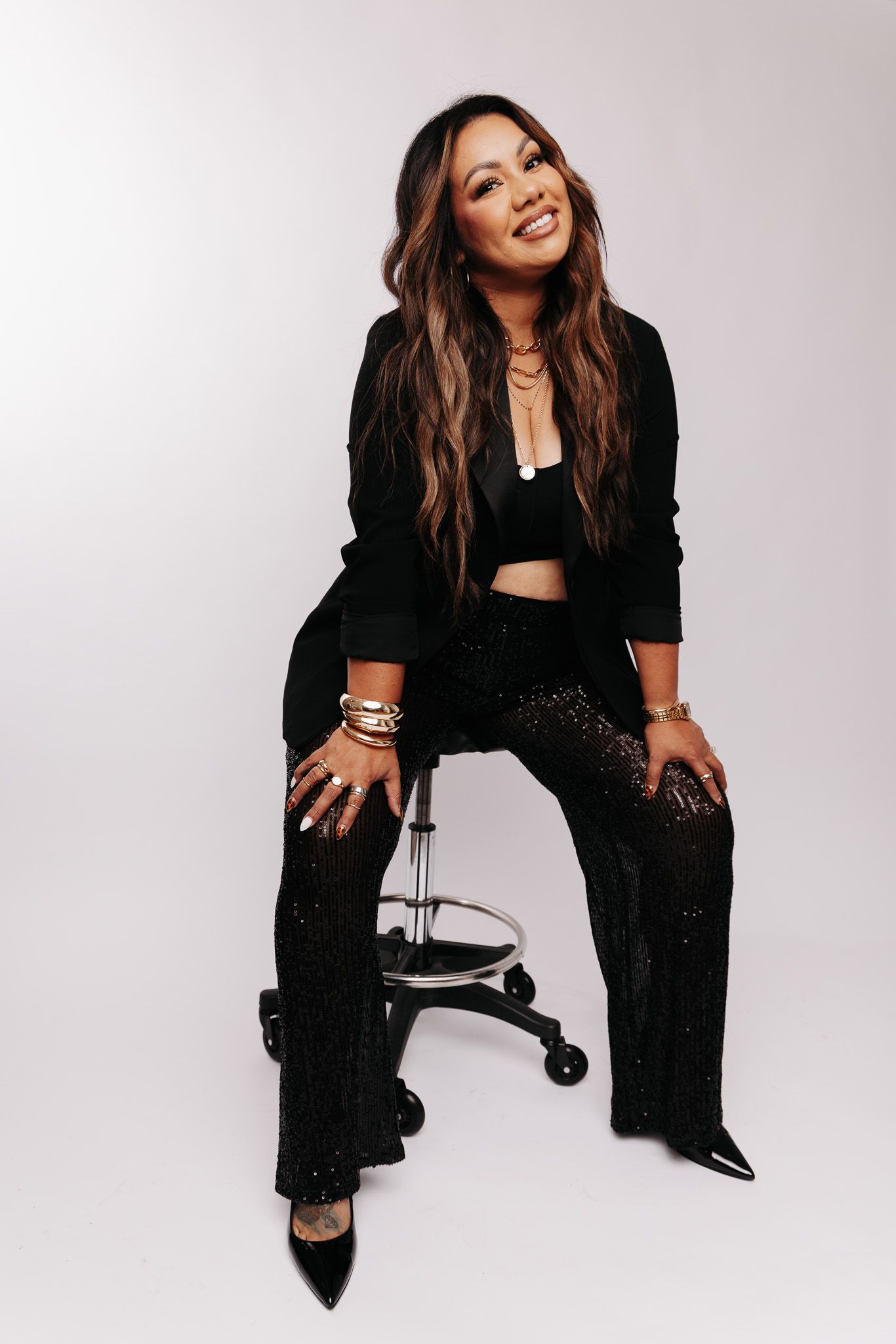 A person in a black outfit poses dynamically against a white background in a fashion photo series.