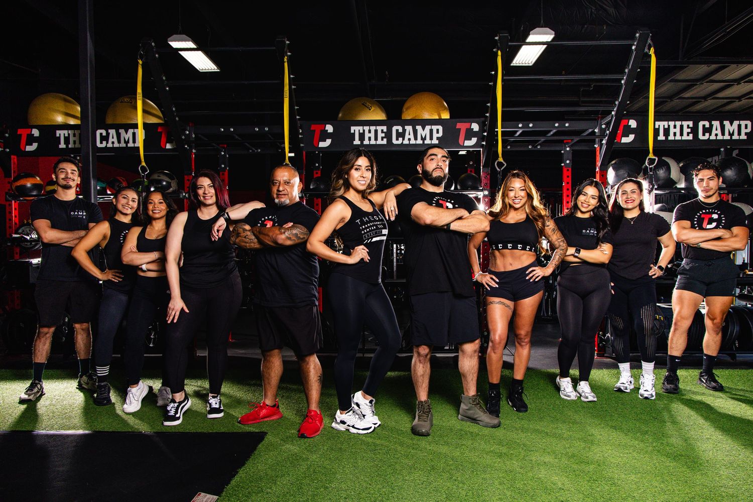 Athletes perform synchronized squats in a dark gym with red lighting during an intense training session.