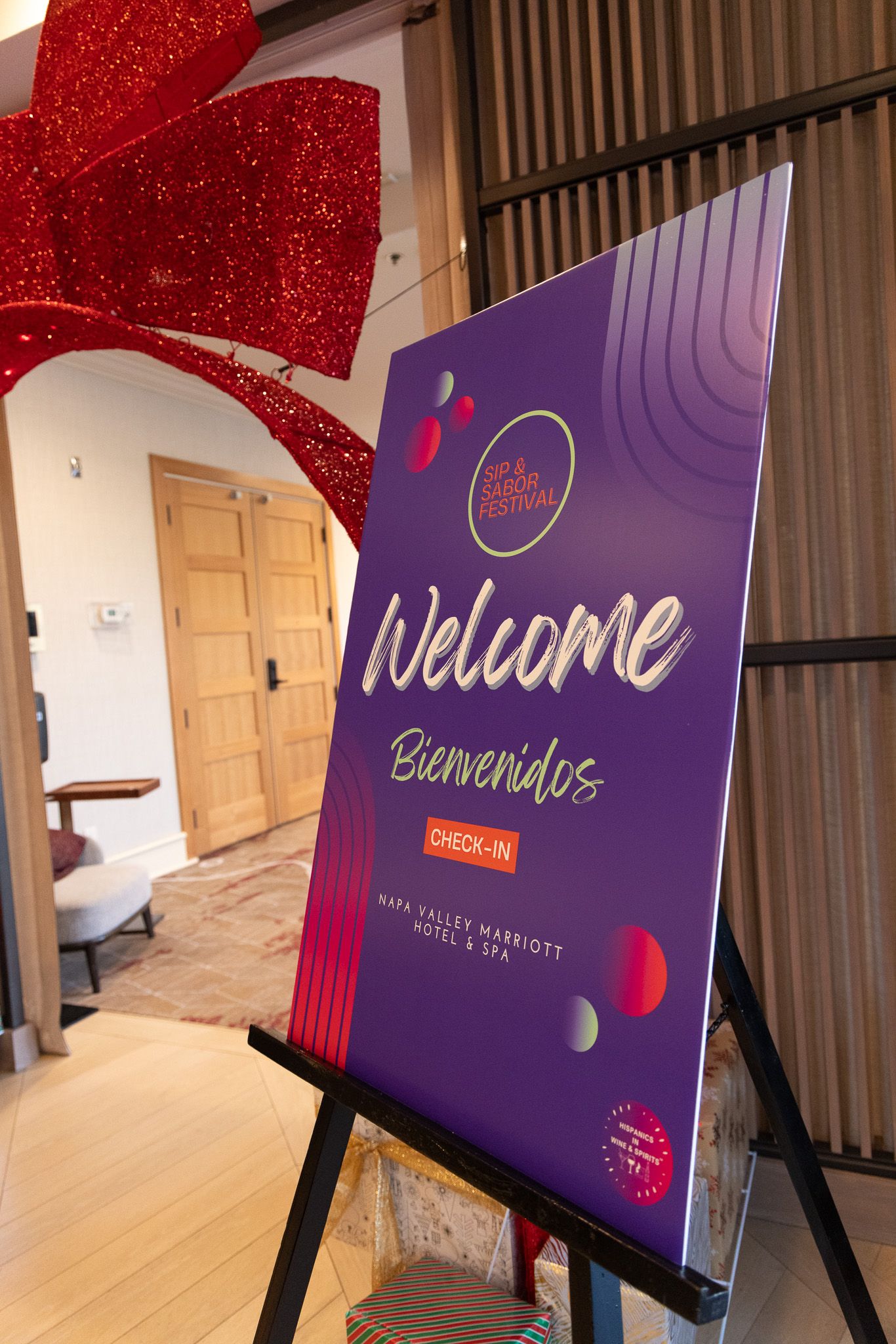 Purple and red welcome signs displayed on easels at a hotel or conference venue entrance.