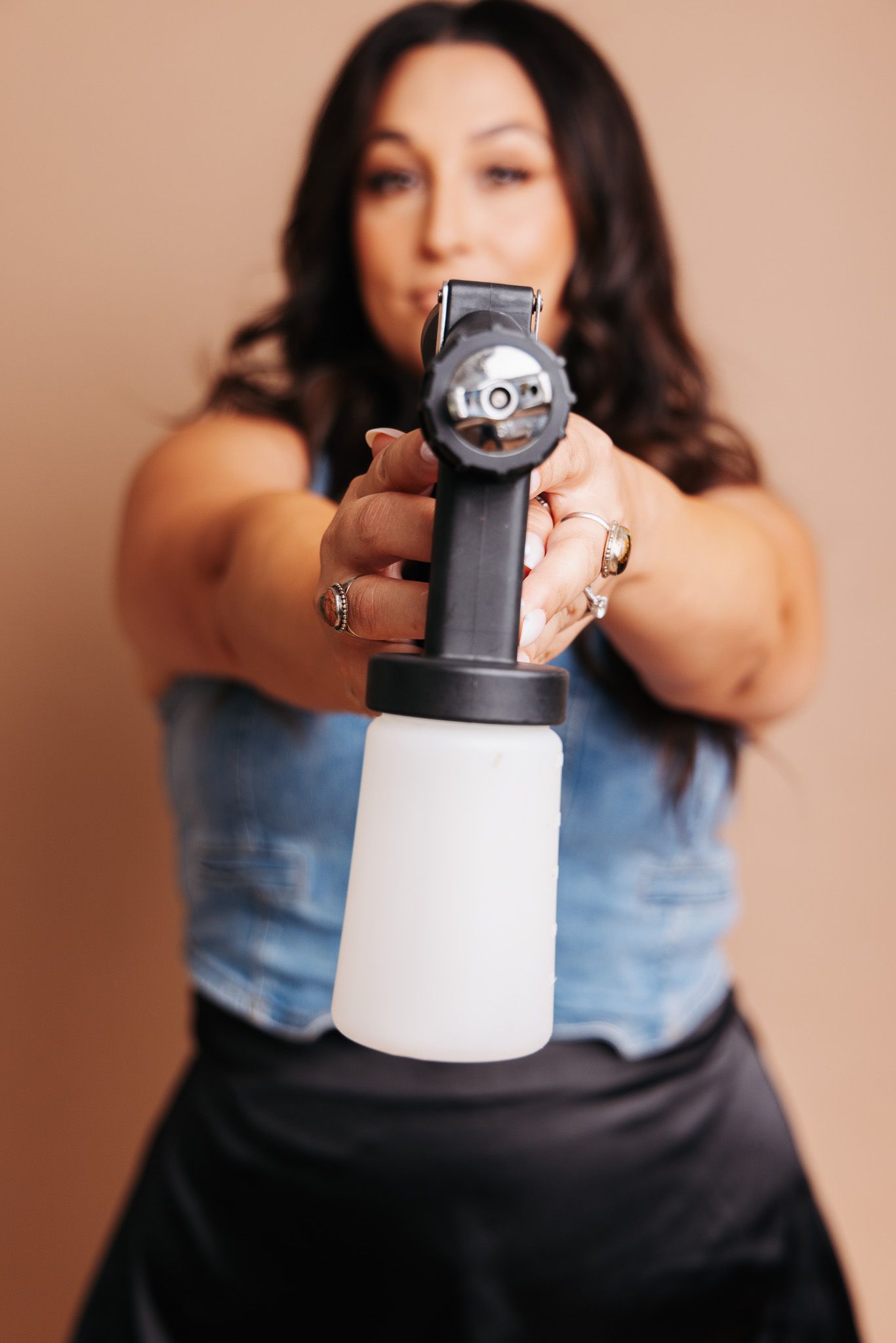 Woman in denim holds an antique bottle sprayer in a sequence showing different angles of the vintage glass object.