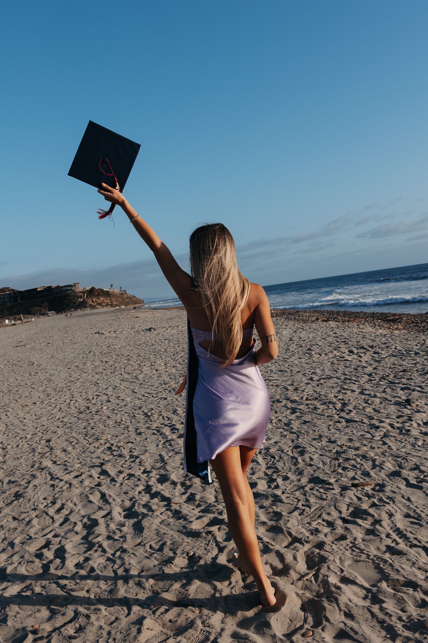 A sequence of photos showing someone dancing and twirling with a document or diploma at sunset on a sandy beach.