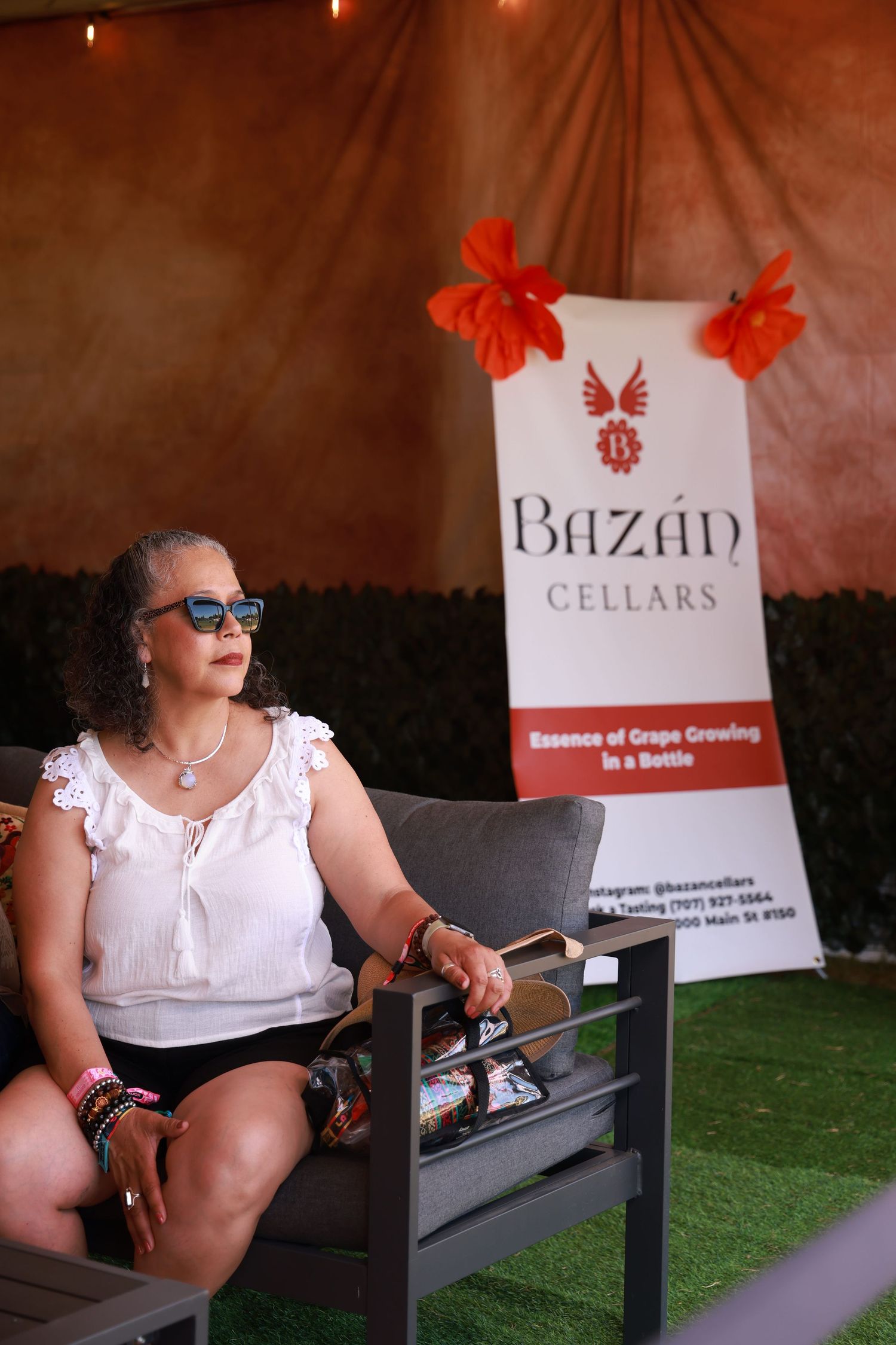 A wine tasting setup at Bazan Cellars with a banner display and outdoor seating area on artificial turf.
