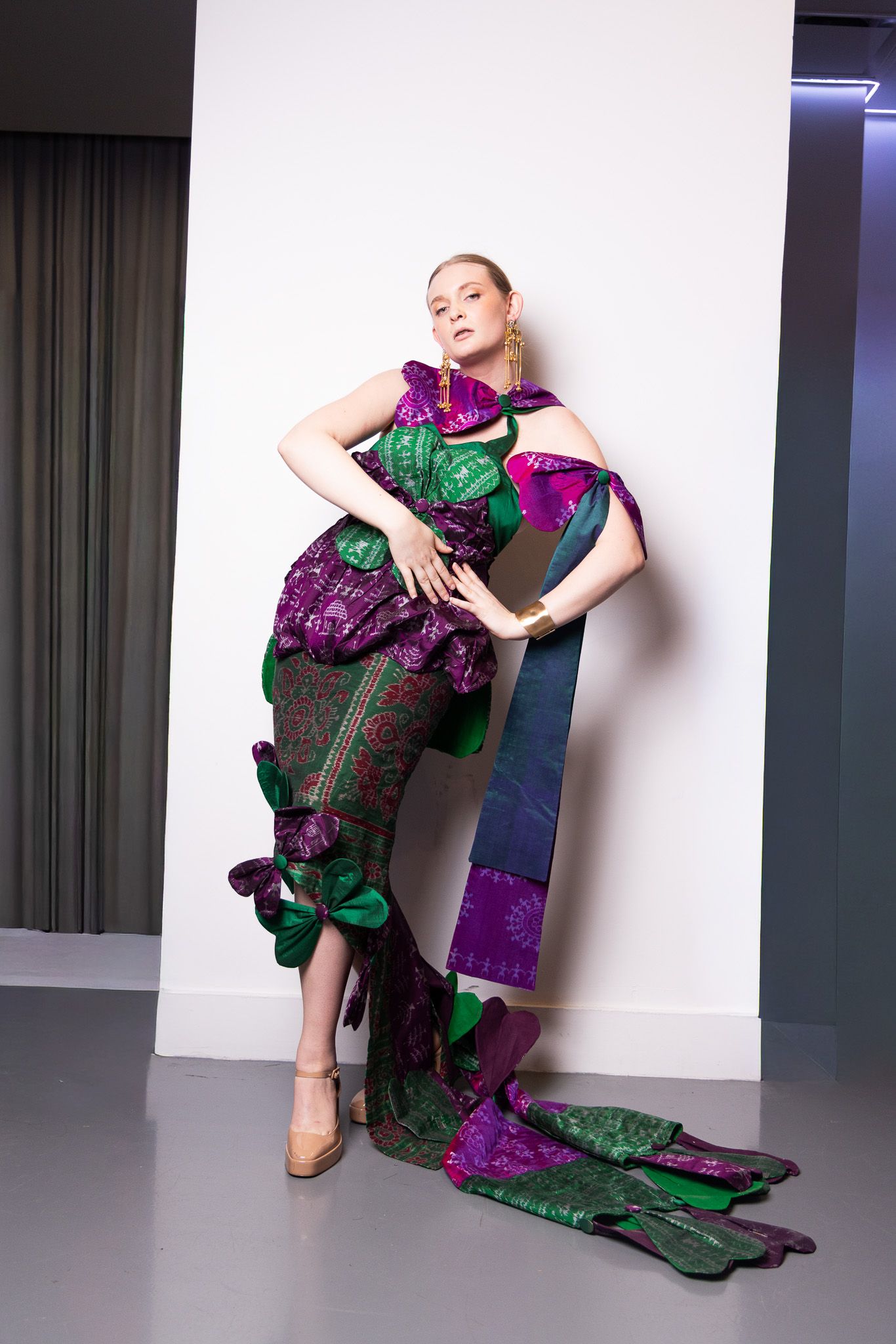 Metallic green and purple evening gown creates dramatic shapes during studio photoshoot.
