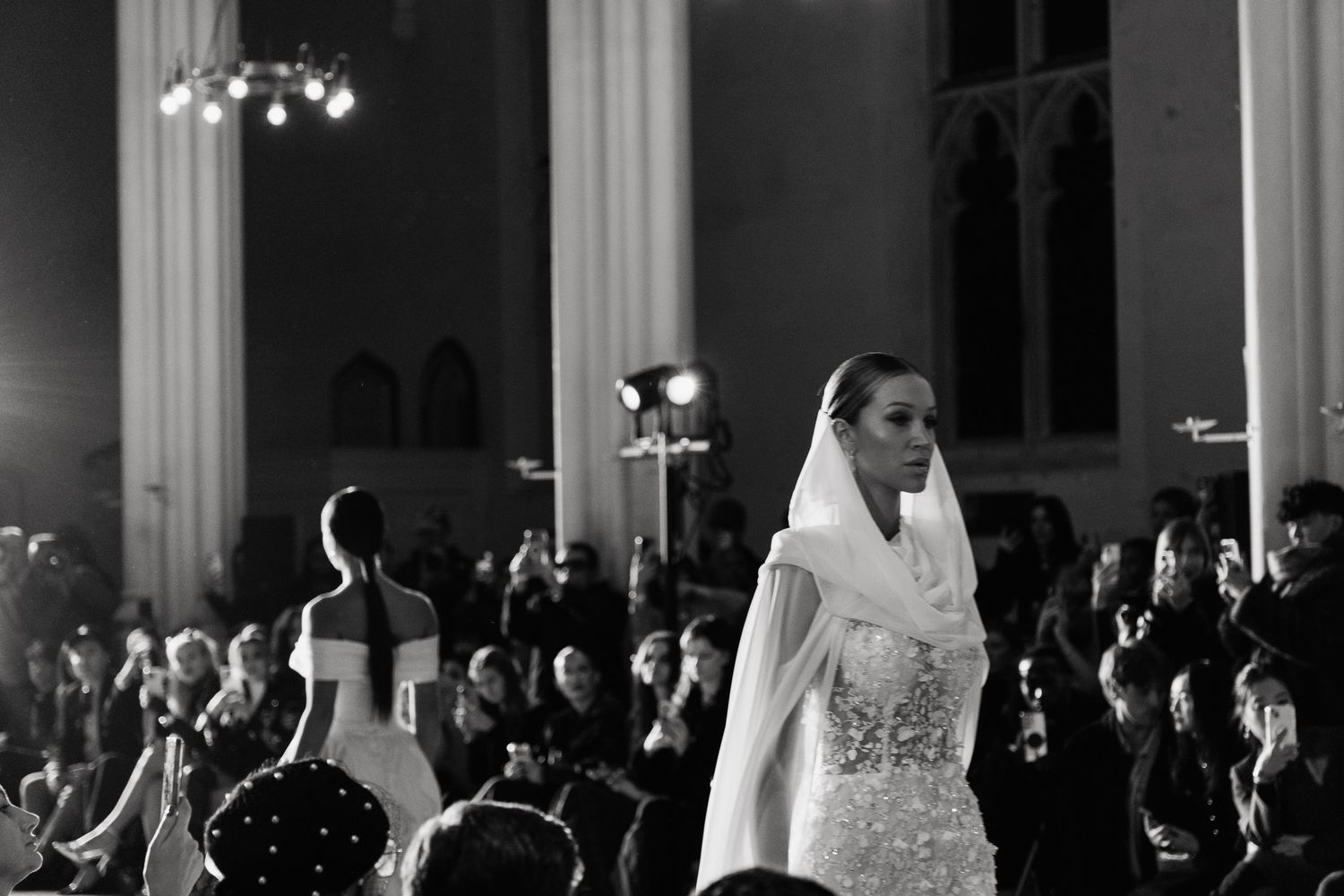 Elegant bridal fashion show with models walking down illuminated runway.