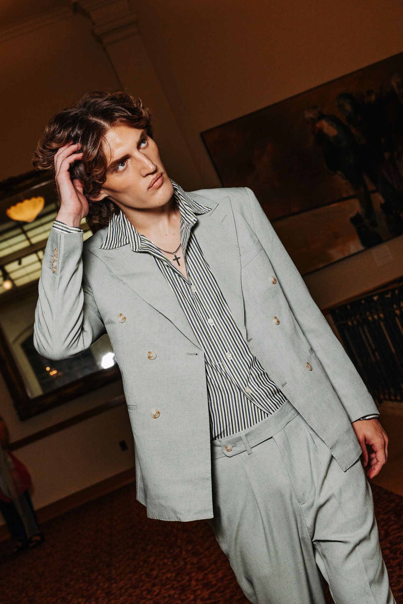 A person poses in a light gray suit with a striped shirt against a dark background in multiple dynamic shots.