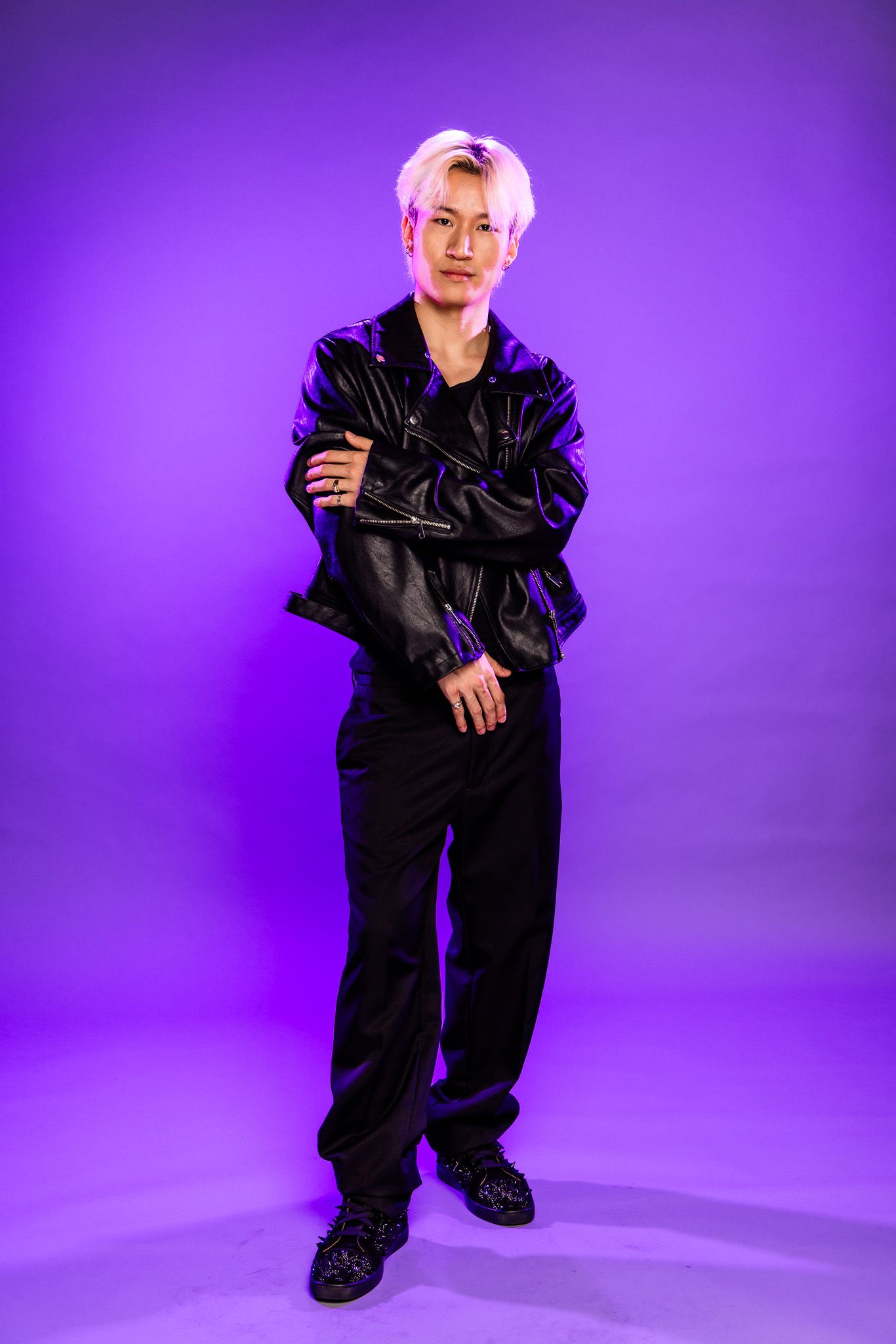 Person in black outfit strikes various poses on purple studio background.