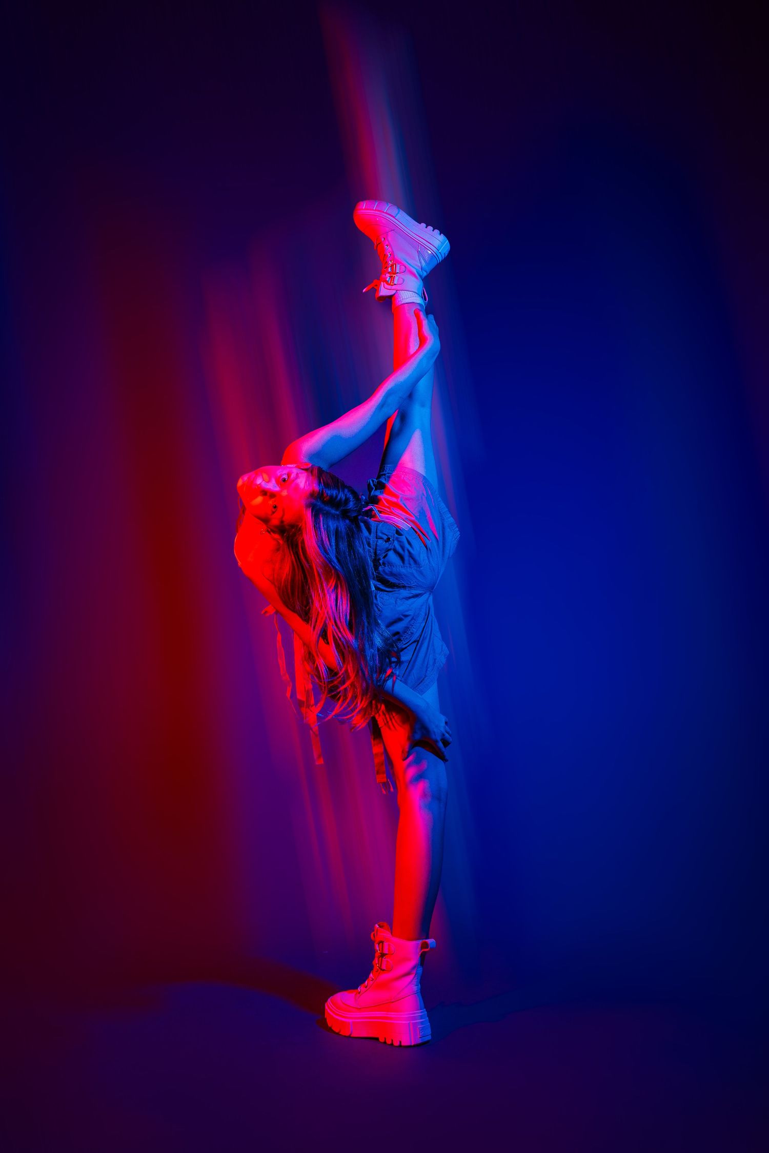 Dramatic dance performance captured in neon red and blue lighting showing fluid body movements.