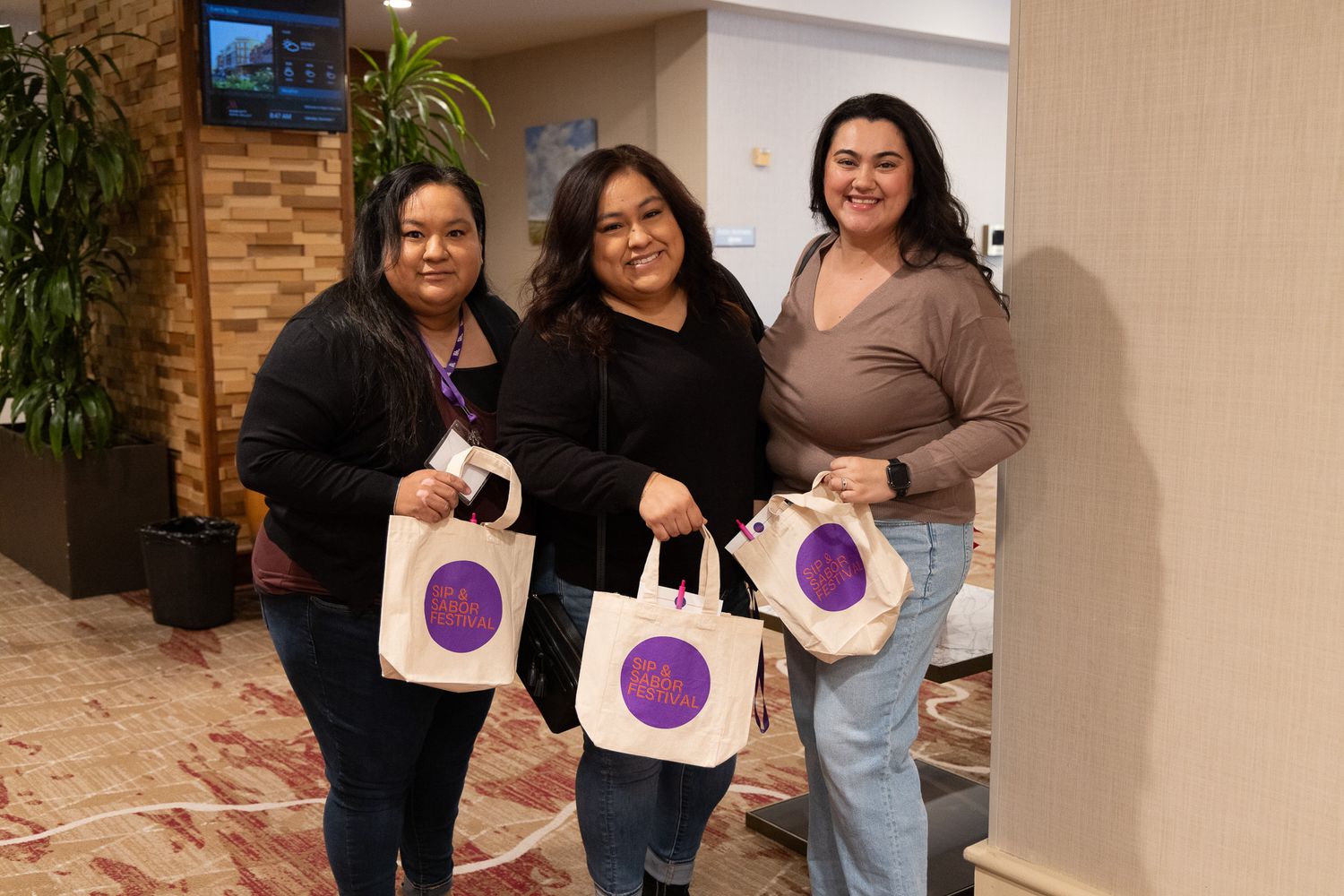 Group holding up purple branded shopping bags at a store opening event.