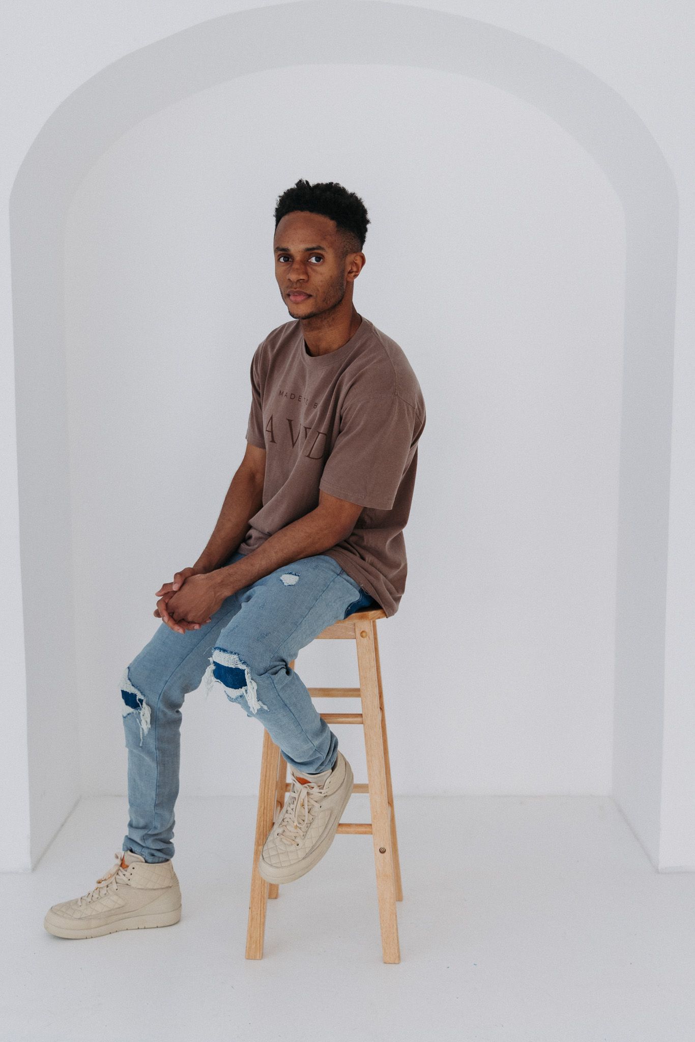 Artistic fashion photo sequence showing model in brown shirt and jeans against white arched background.