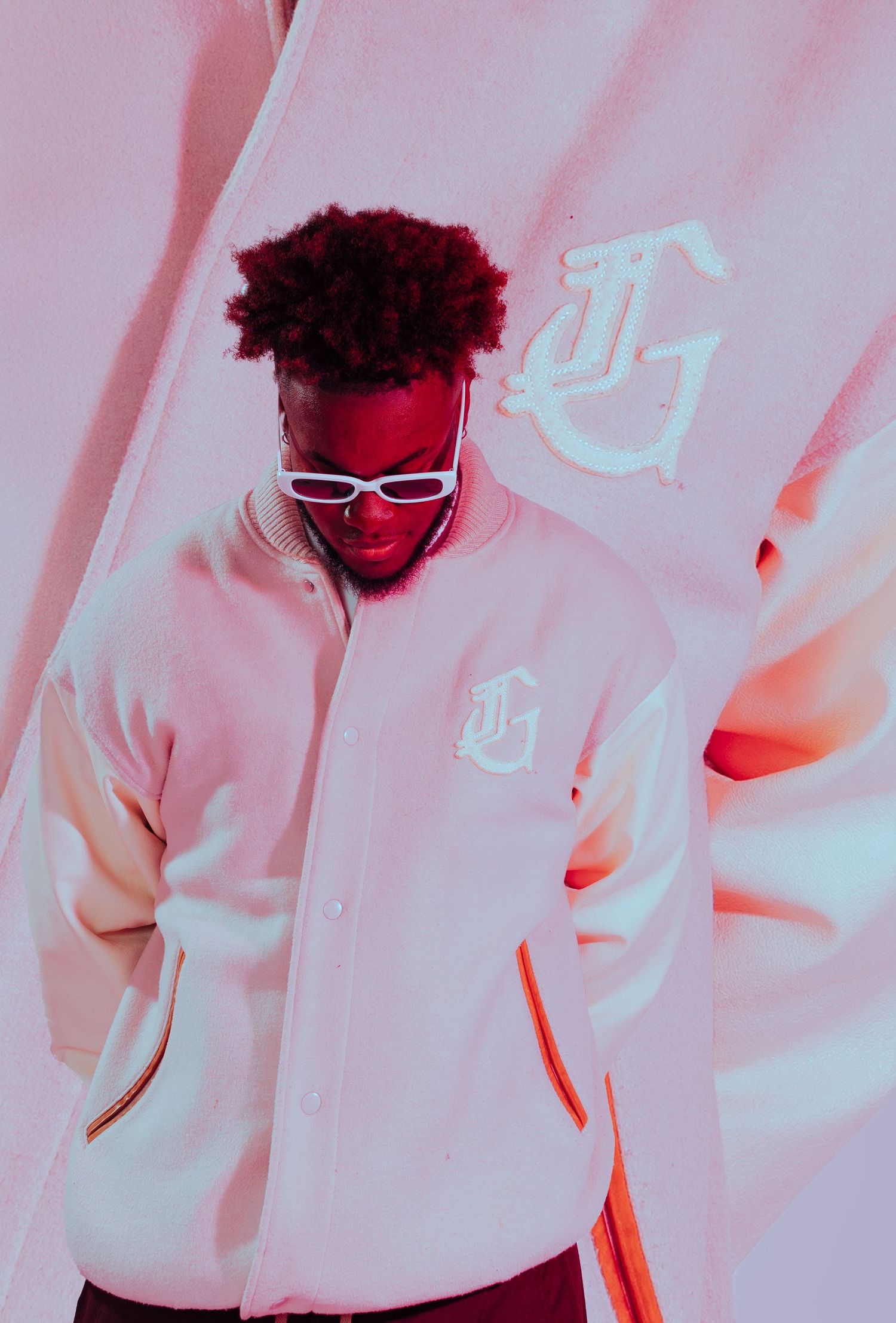 Artistic portrait photo with neon pink and blue lighting showing a person in white clothing against a soft gradient background.