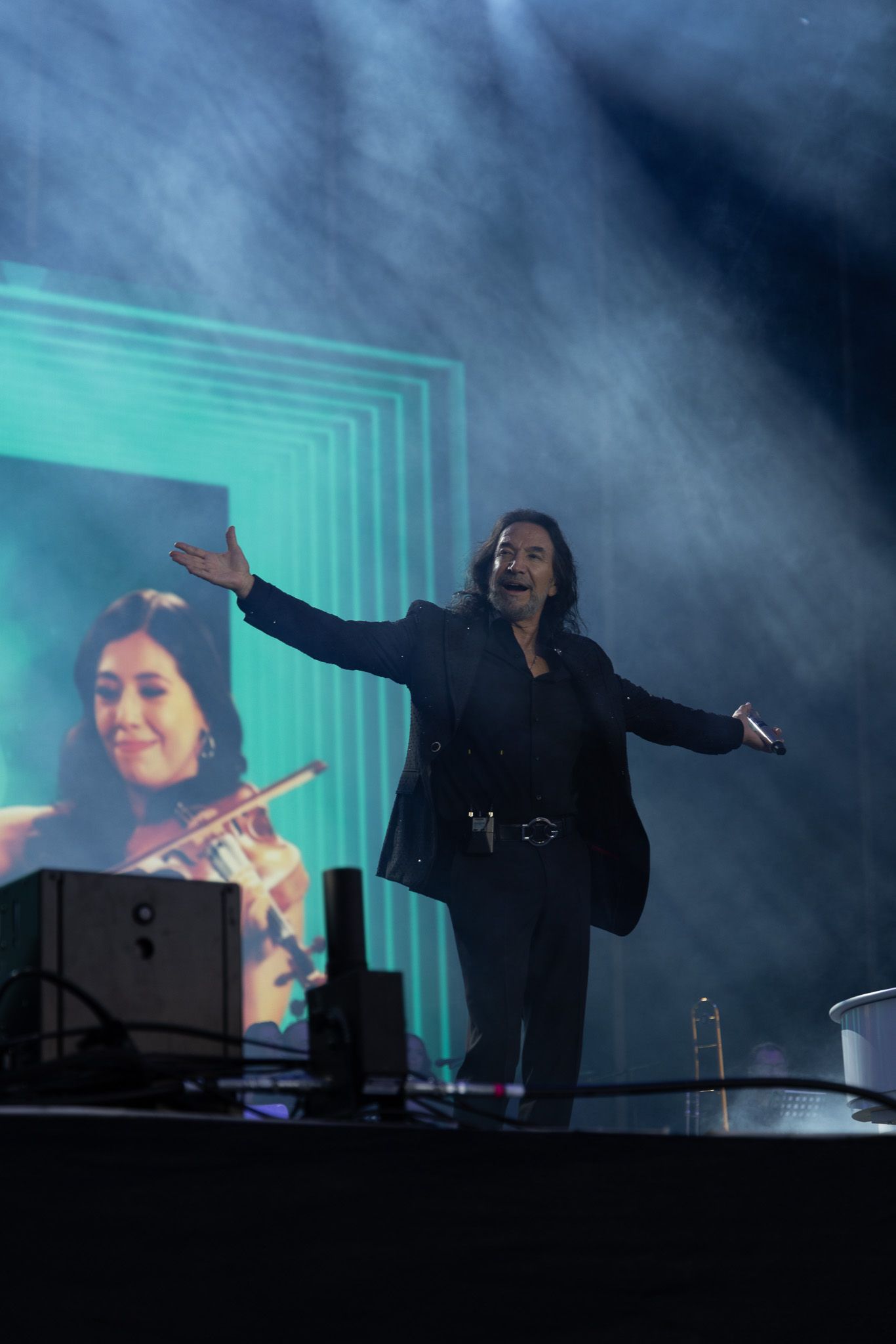 Atmospheric concert performance with silhouettes against blue lighting and geometric backdrop.