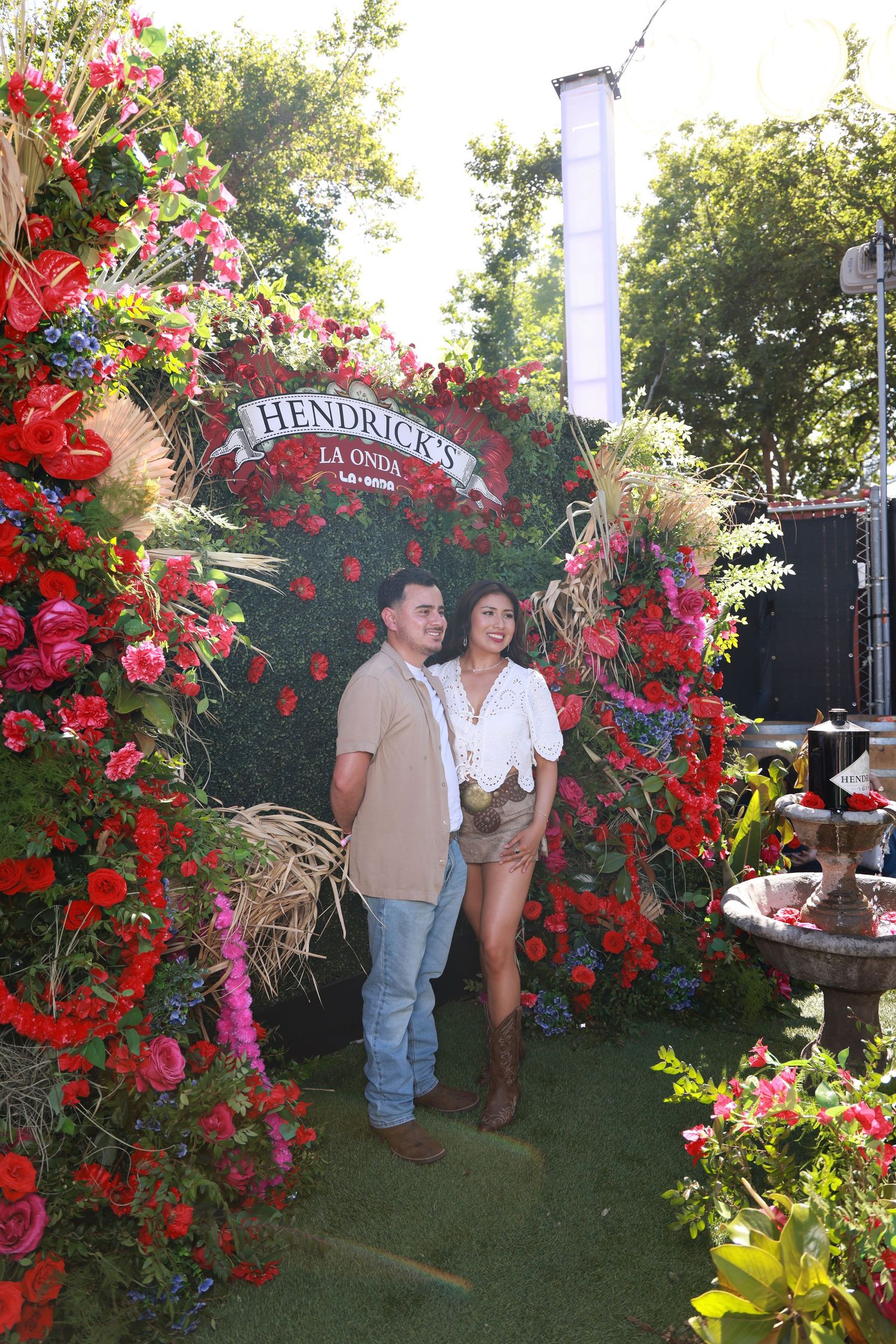 Beautiful floral display with red roses and decorative arch featuring Hendrick's branding at an outdoor event.