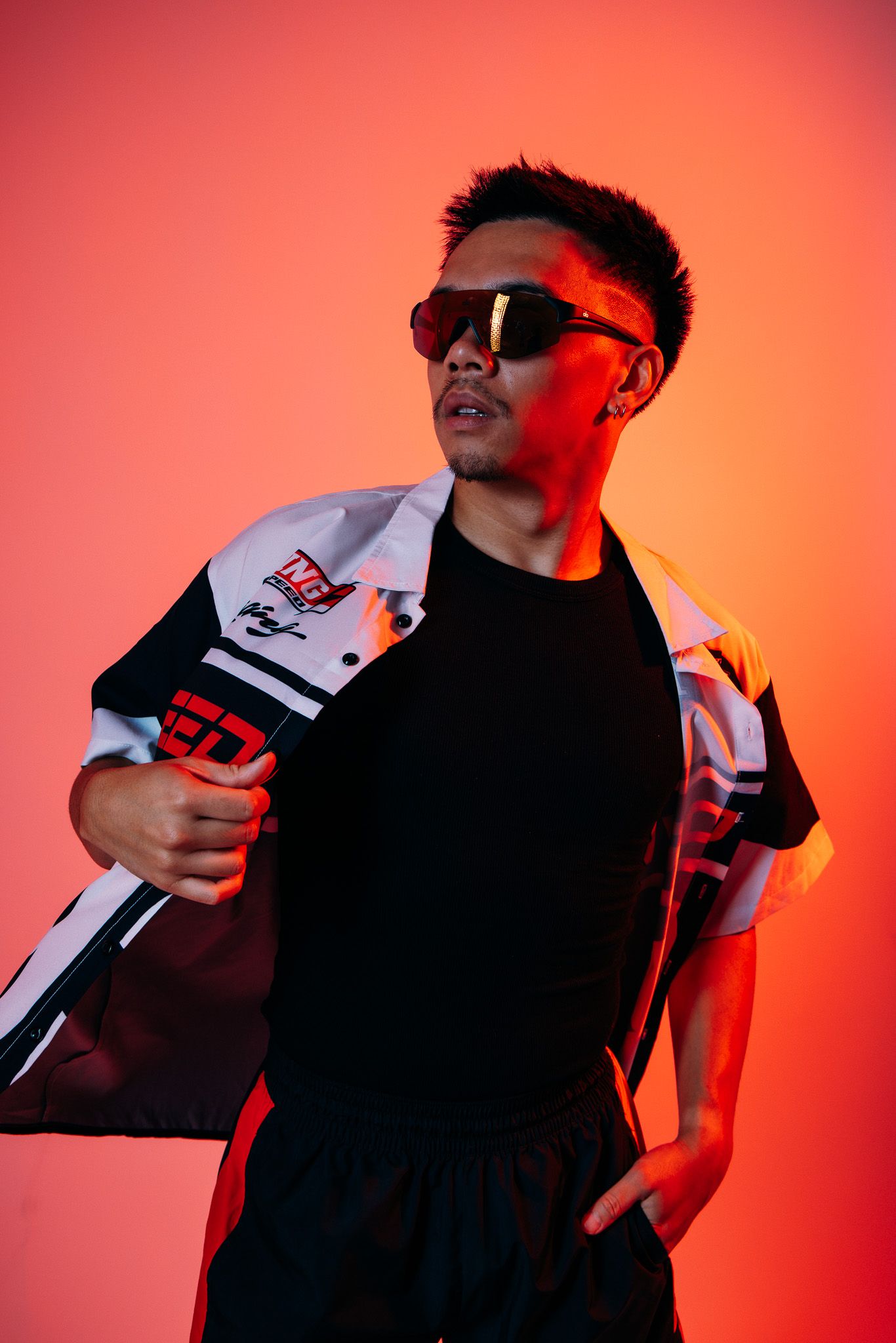 Someone wearing sunglasses and black clothing poses against a vibrant red background in a series of fashion photos.