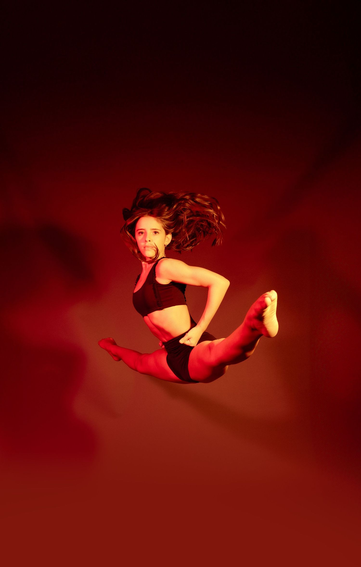 Dynamic dance movements captured in dramatic red lighting showing graceful leaps and poses.