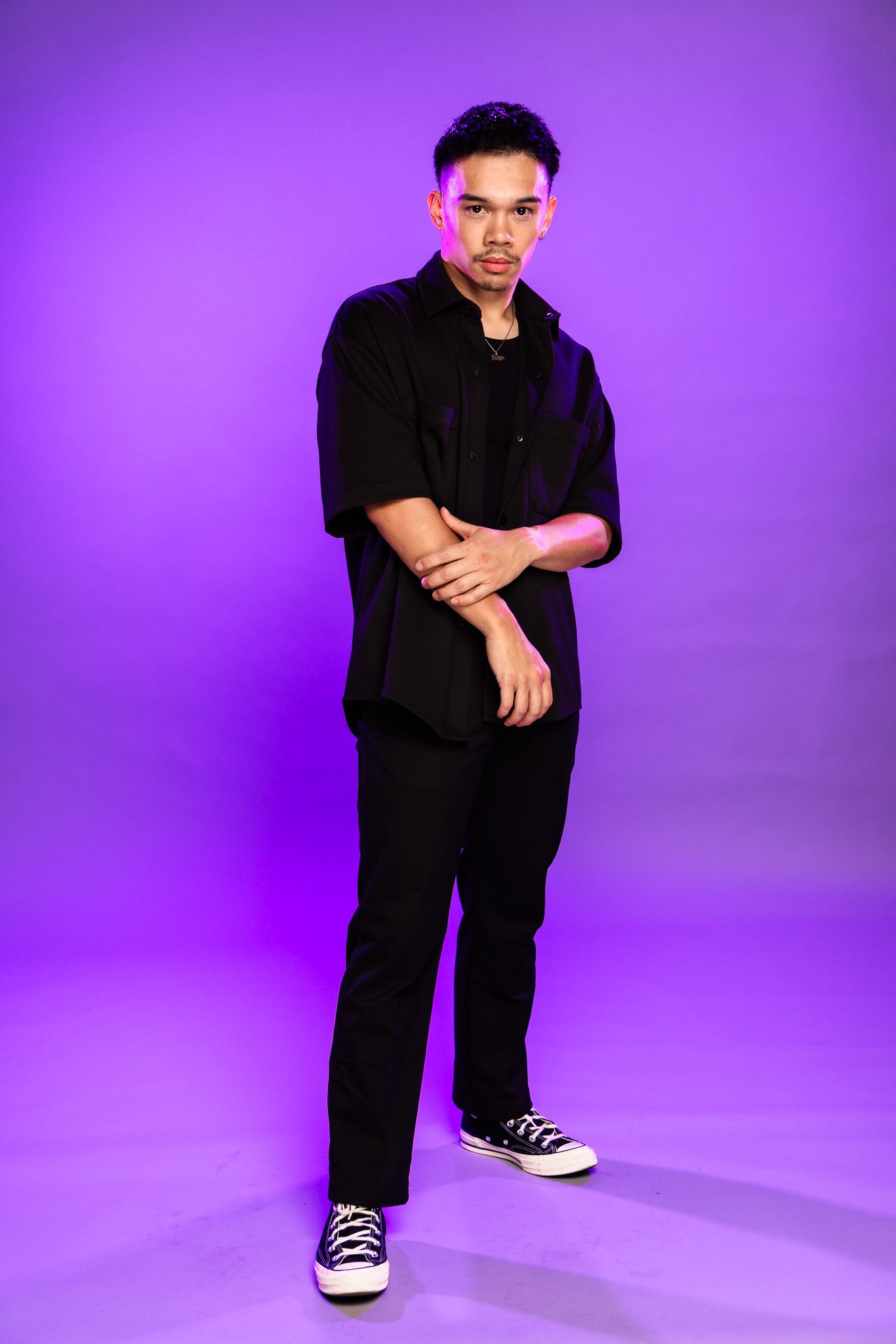 Person in all black attire poses against vibrant purple backdrop in four dynamic studio shots.