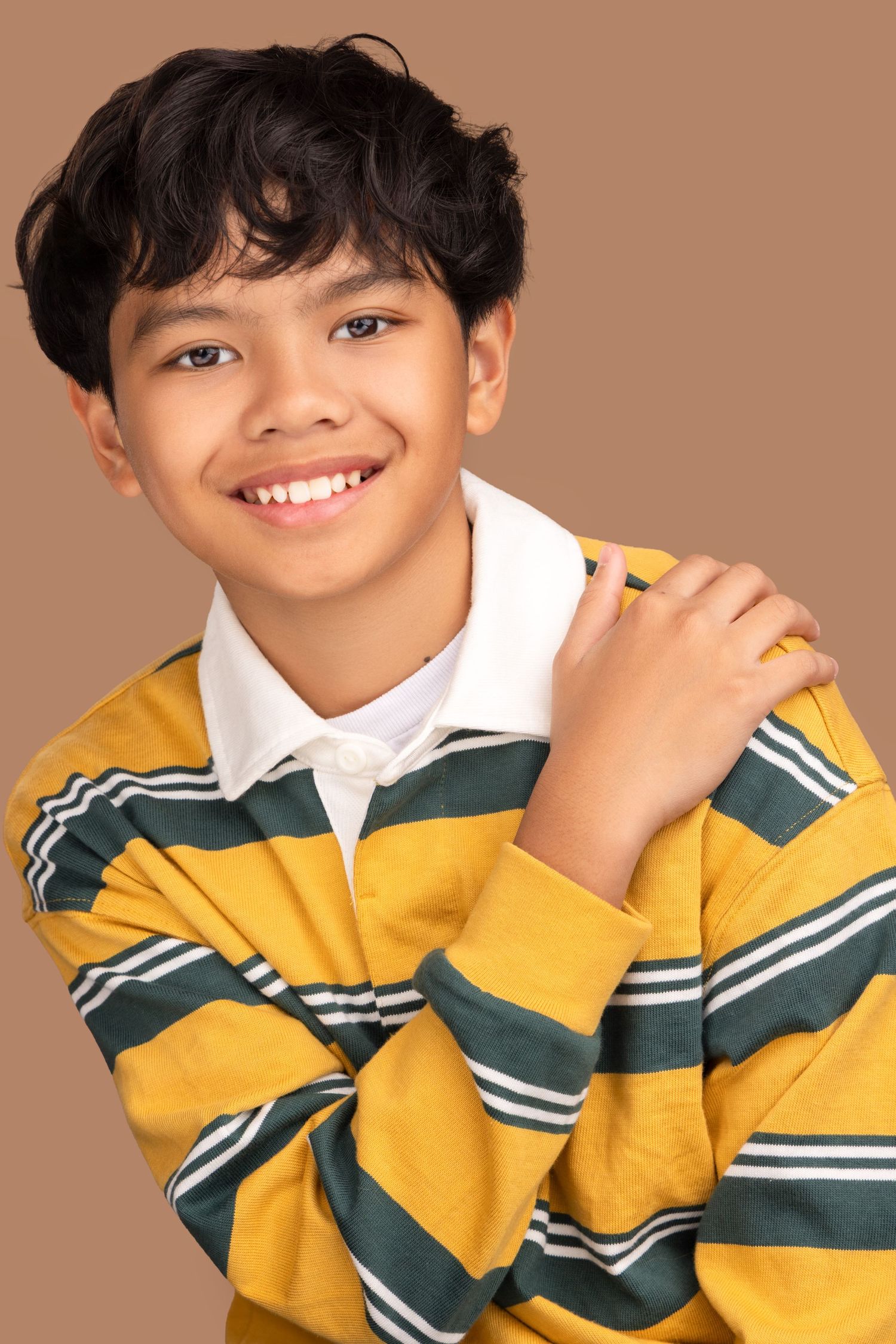 A young person wearing a yellow and green striped rugby shirt with white collar poses playfully in a photo series.