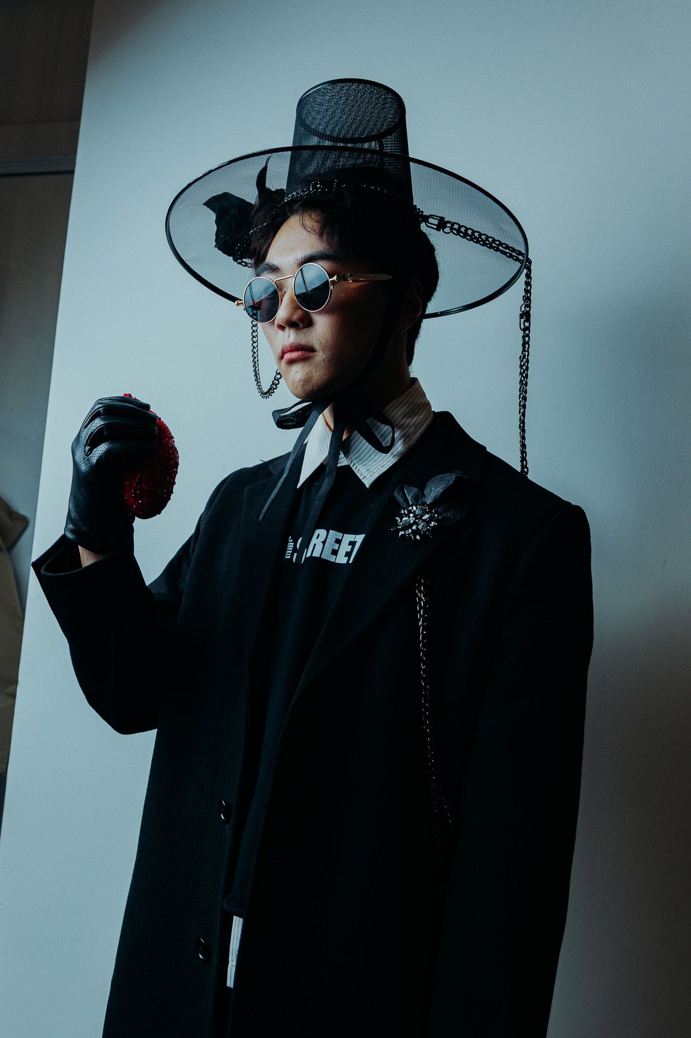 Moody fashion portraits featuring a figure in dark clothing and wide-brimmed hat against blue backdrop.