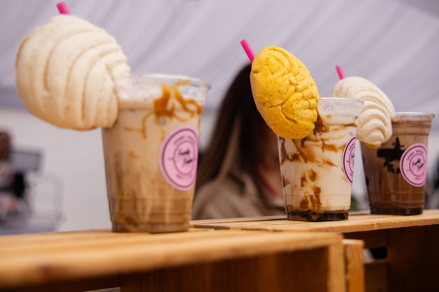 Artisanal desserts and pastries displayed on a wooden surface with pink accents.