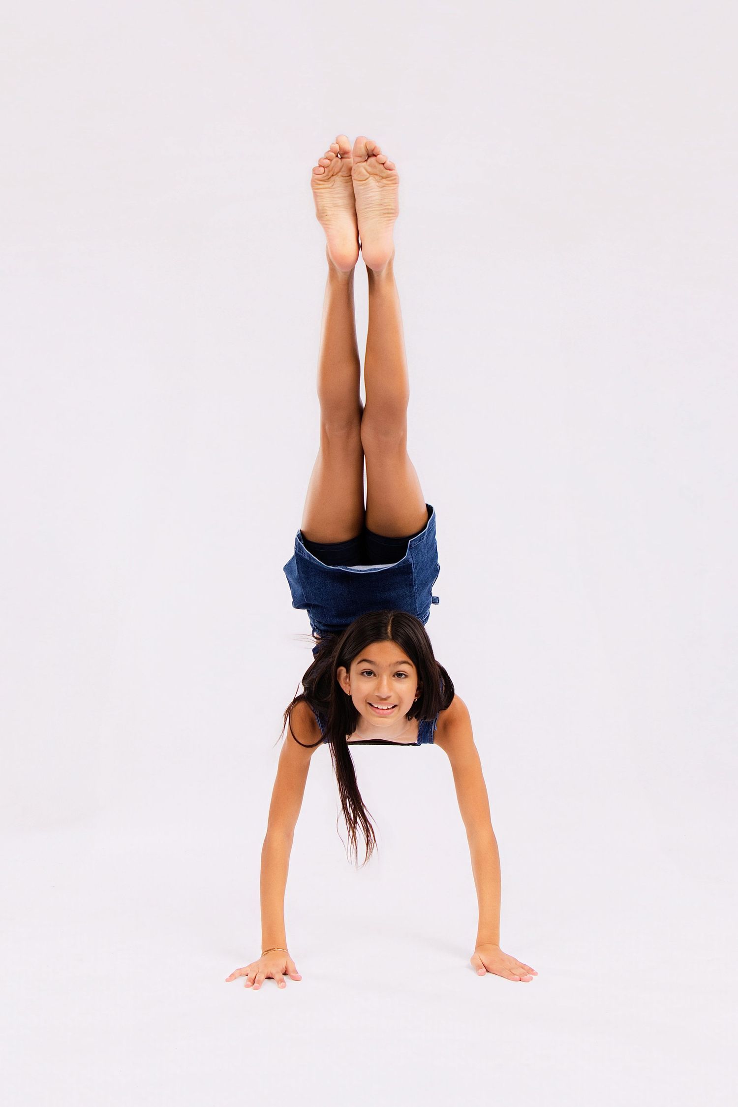 Dancer executes handstand variations and floor work in denim outfit.
