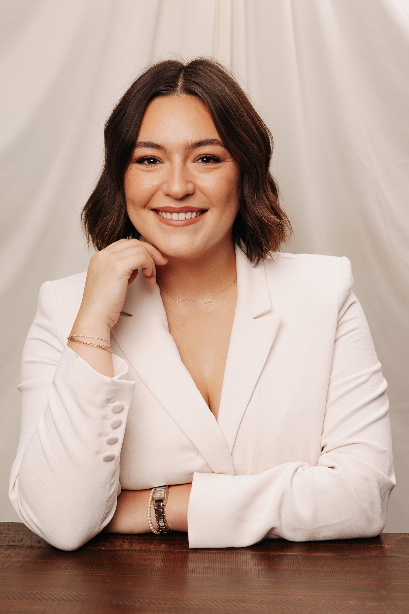 Professional portrait series showing someone in a white blazer posing against a light background.