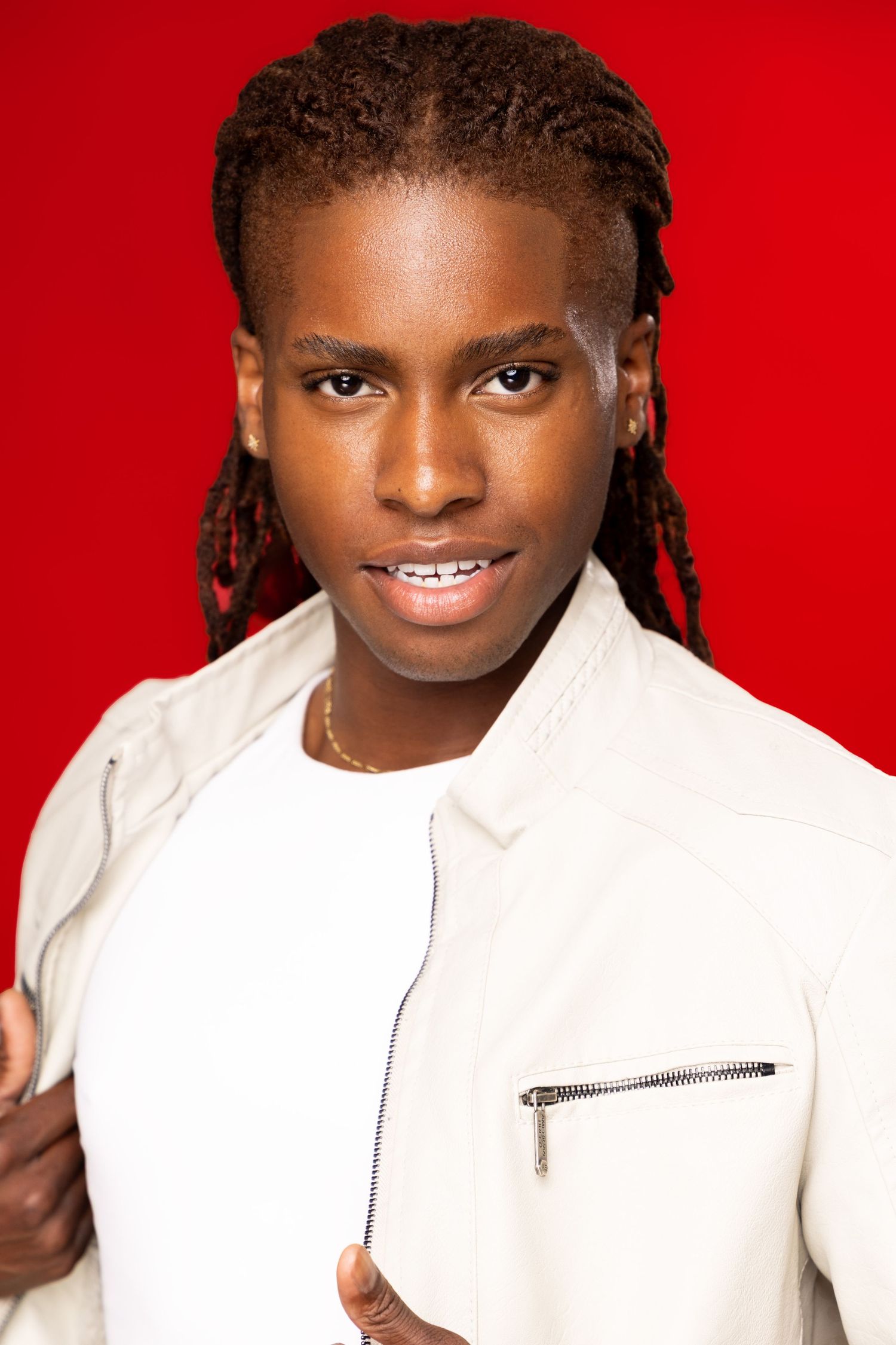 Portrait against a red background wearing a white collared shirt.
