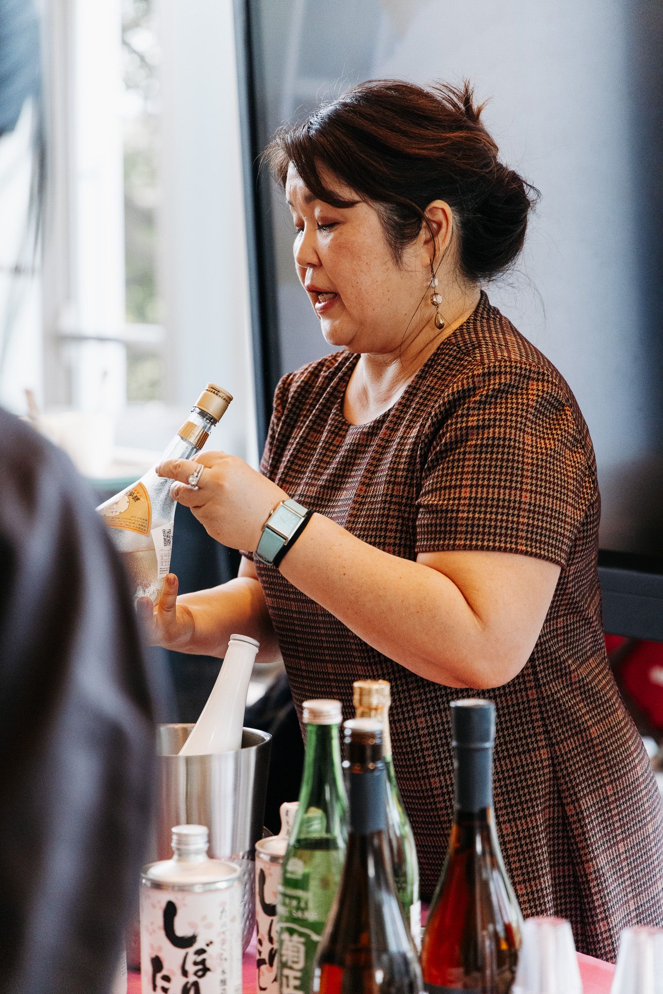 Person in brown checkered shirt checking their smartwatch during a tasting event.