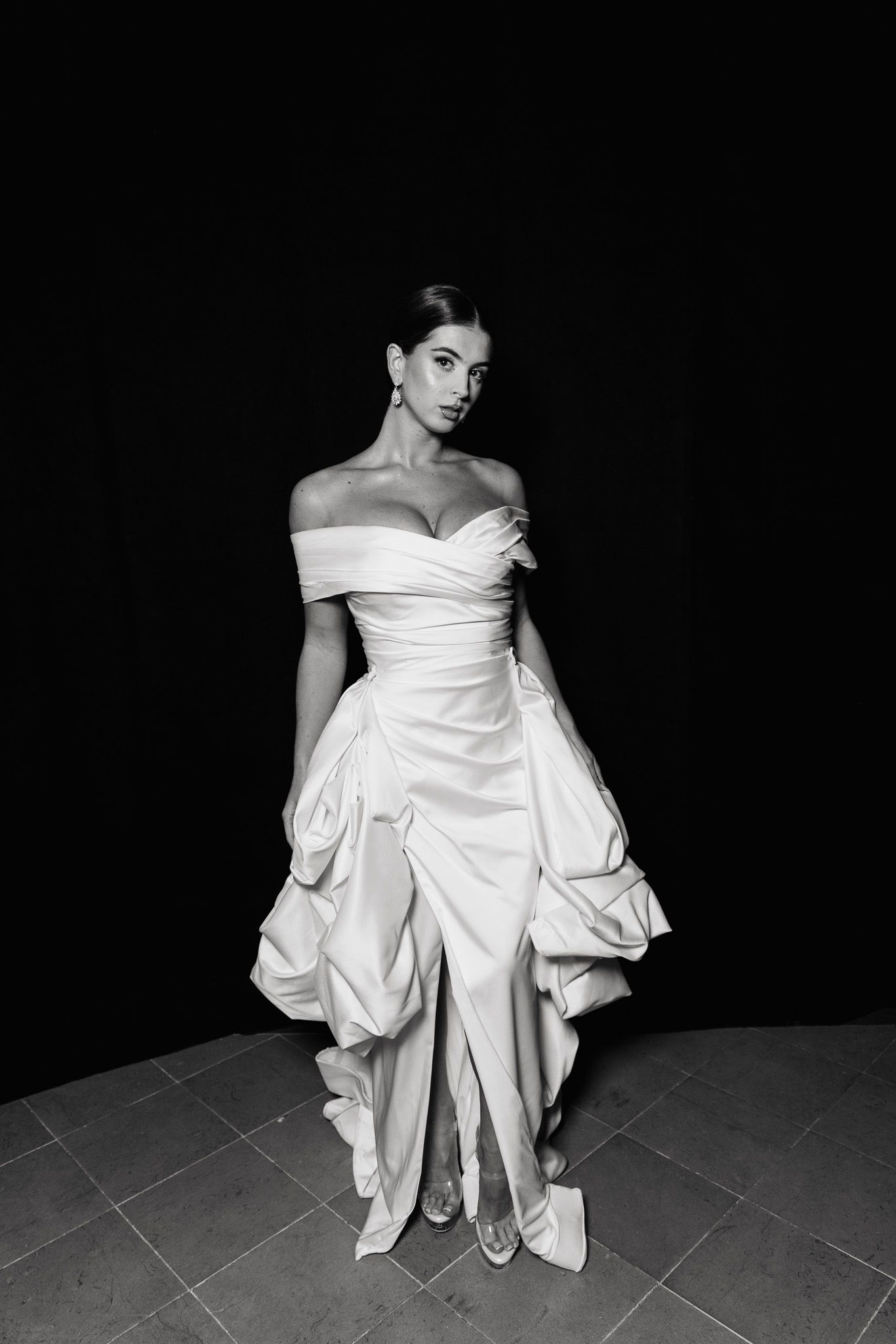 Dramatic black and white fashion series showing a white off-shoulder gown with voluminous sleeves against dark background.