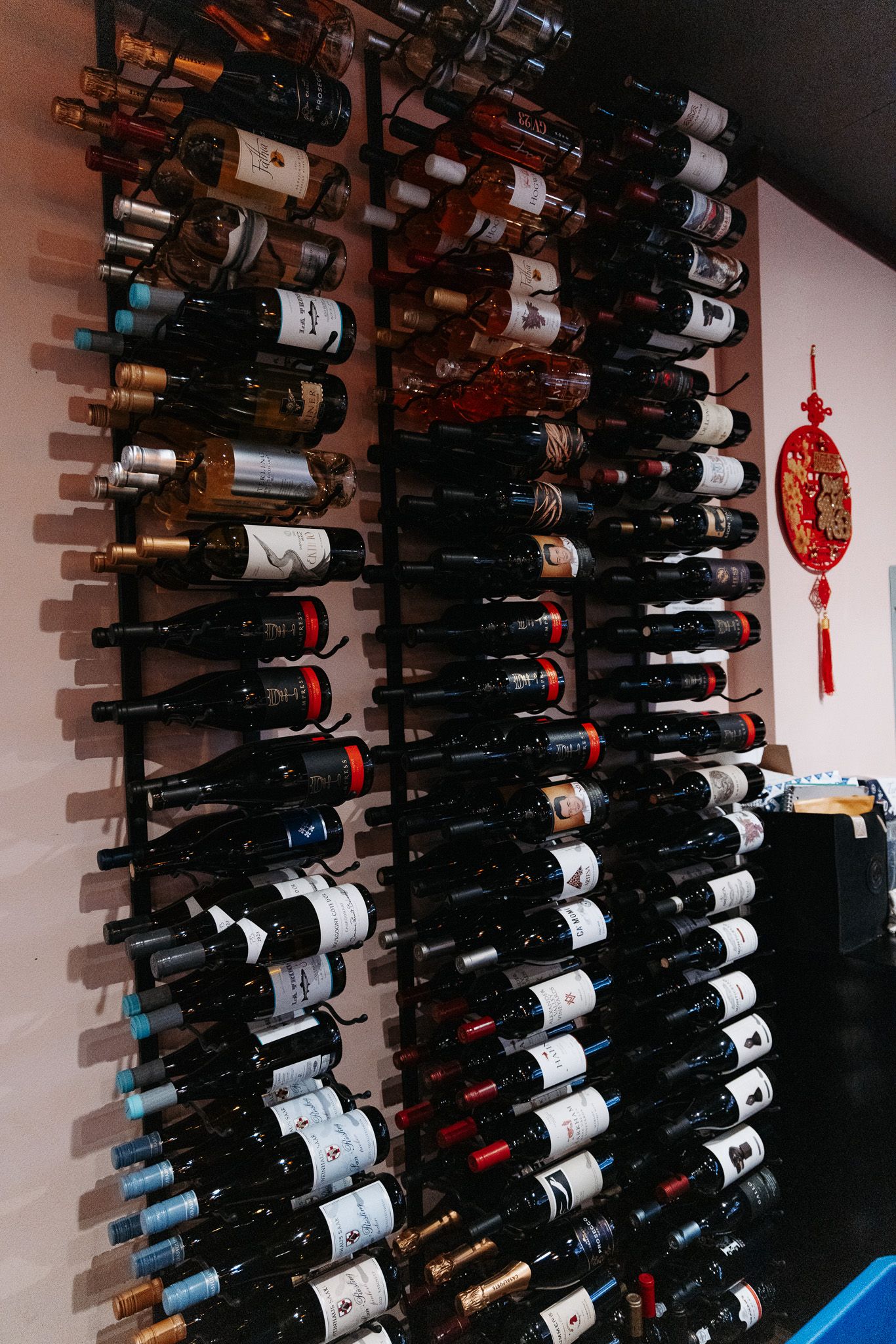 Large wine collection displayed on wall-mounted racks with bottles arranged horizontally against white walls.