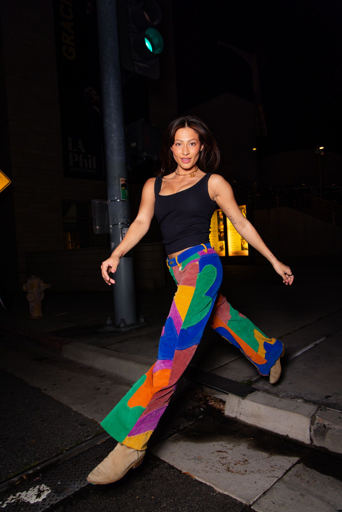 Dancer in colorful geometric patterned outfit performs dynamic poses against dark urban backdrop at night.
