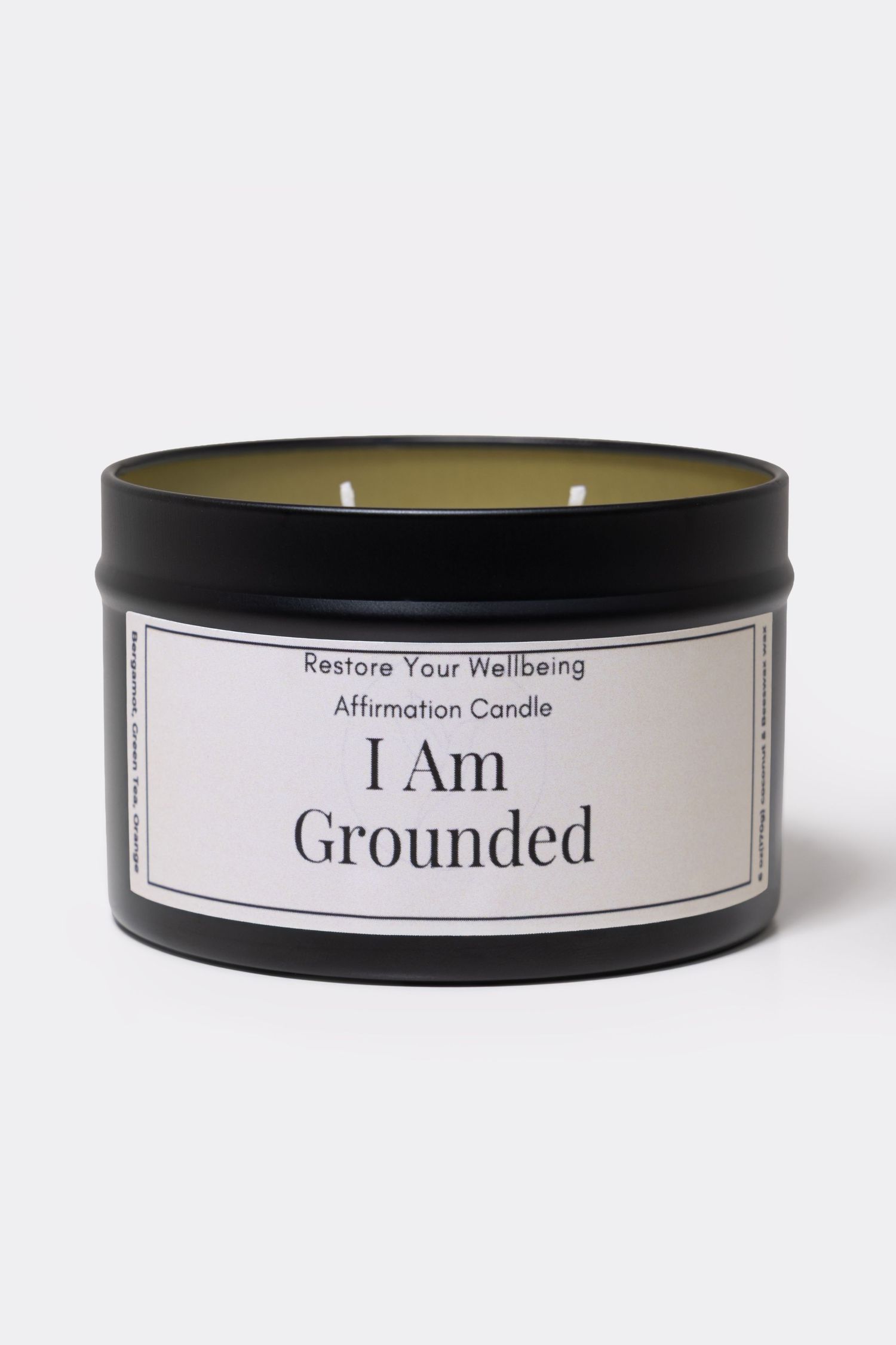 Black tin affirmation candle labeled 'I Am Grounded' by Restore Your Wellbeing, featuring two wicks.