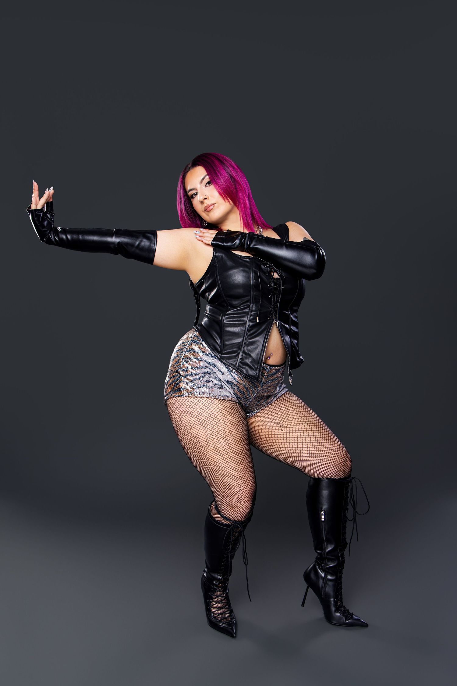 Woman in black leather corset, fishnet tights, and knee-high boots striking a bold pose.