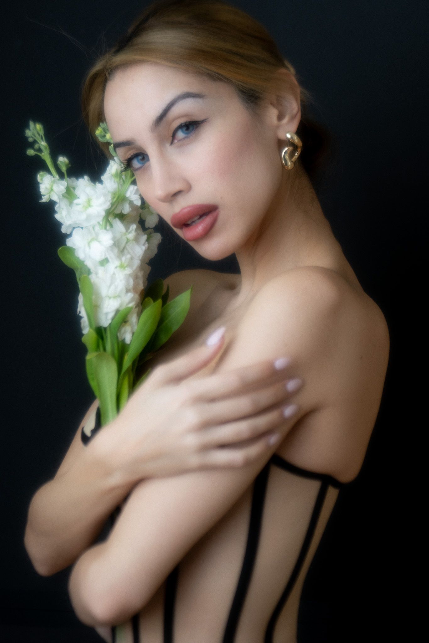 Artistic portrait series with white gladiolus flowers against dark background featuring dramatic lighting and poses in black attire.