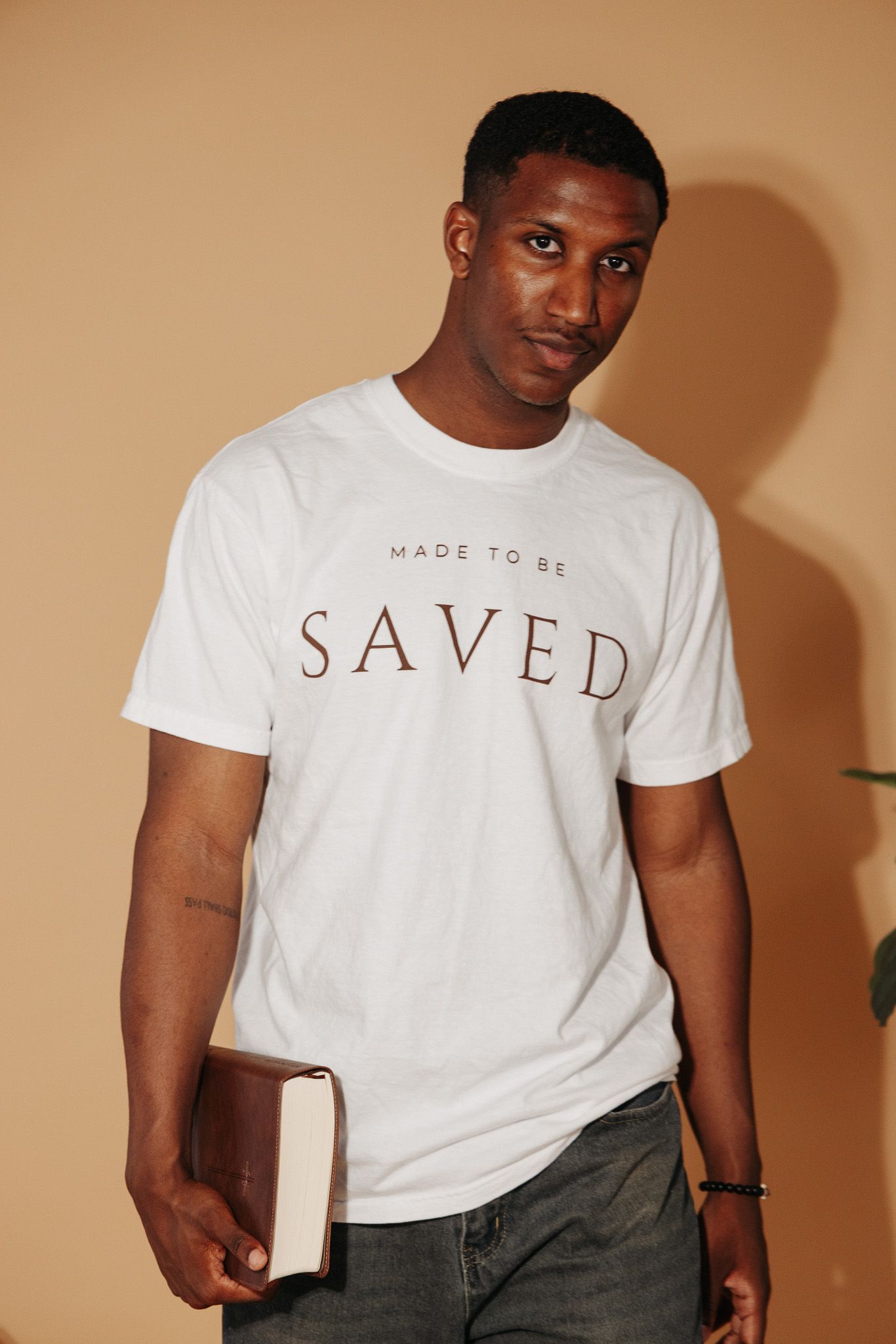 A series of fashion photos showing white t-shirts with minimal text designs styled with dark pants.