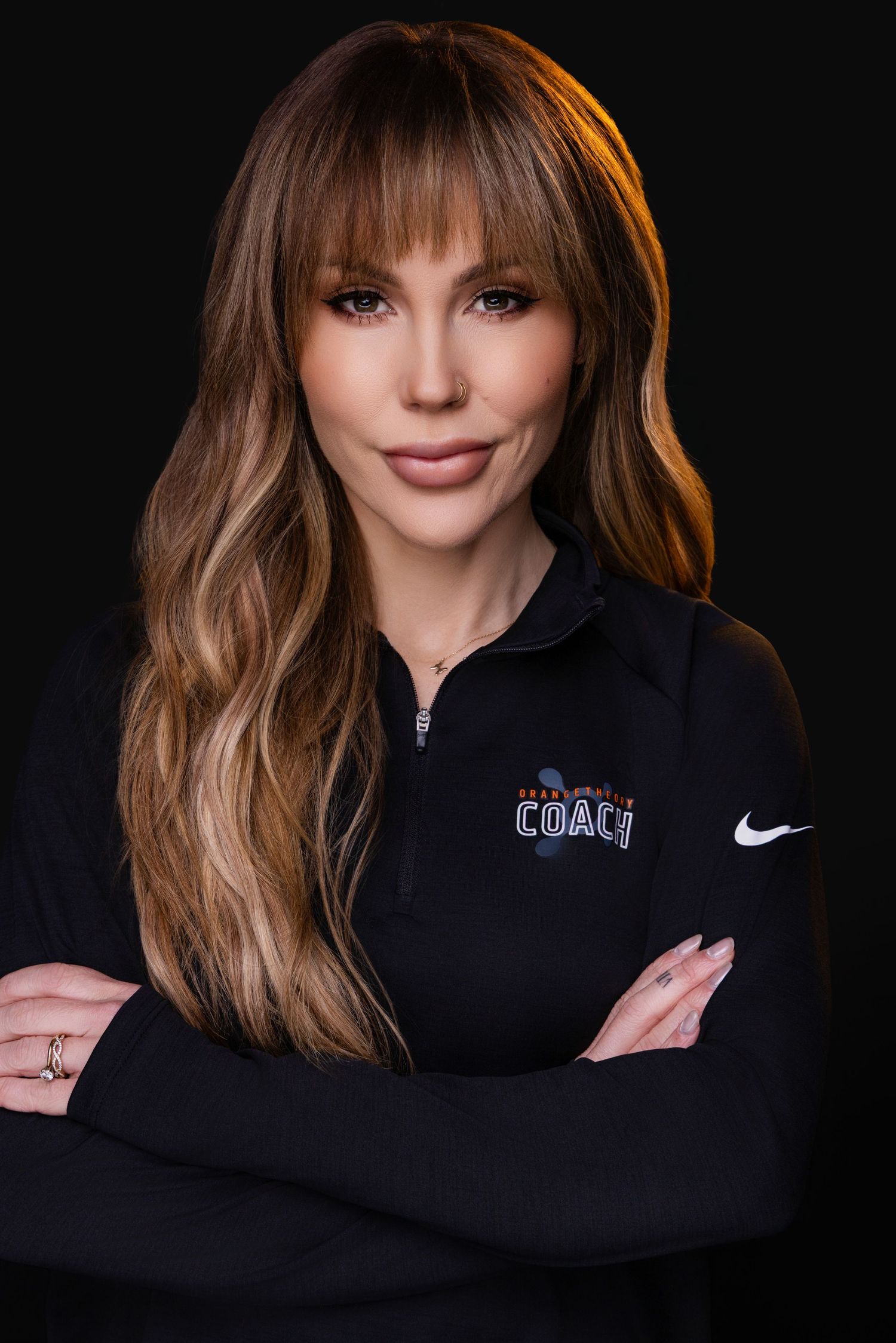 Professional studio portrait in black outfit against dark background with dramatic side lighting creating moody atmosphere.