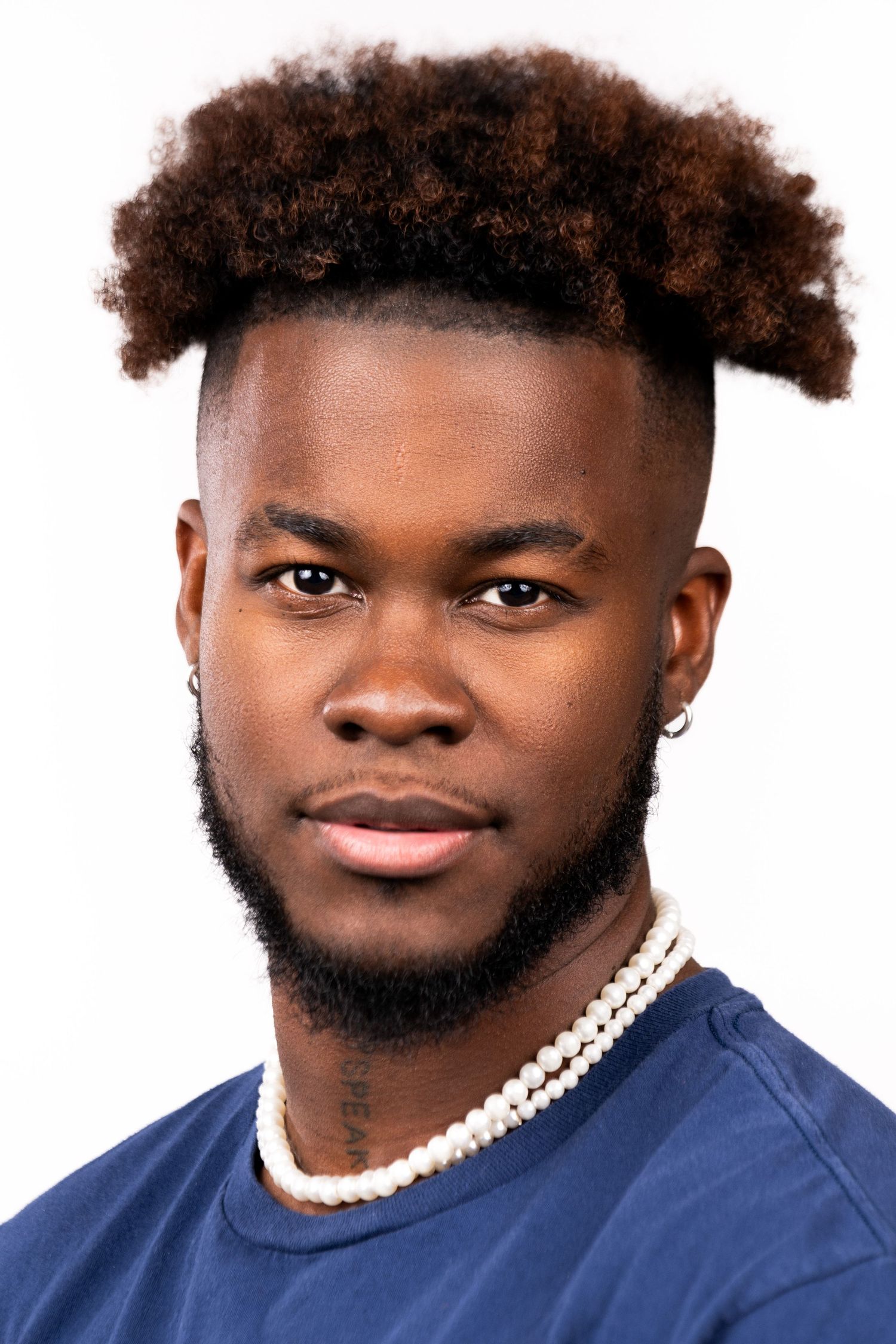 A series of portrait photos showing different angles and expressions in front of a white backdrop while wearing a blue shirt.