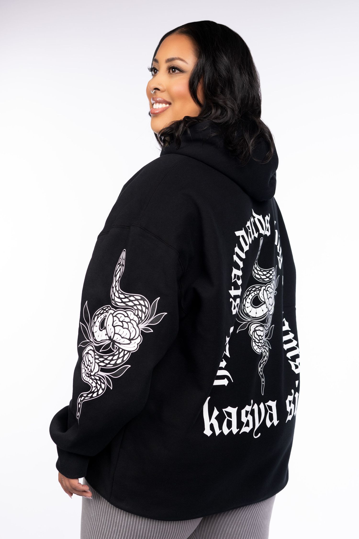 Black oversized hoodie with white snake and floral graphic print, gothic lettering reading kasya s on back.