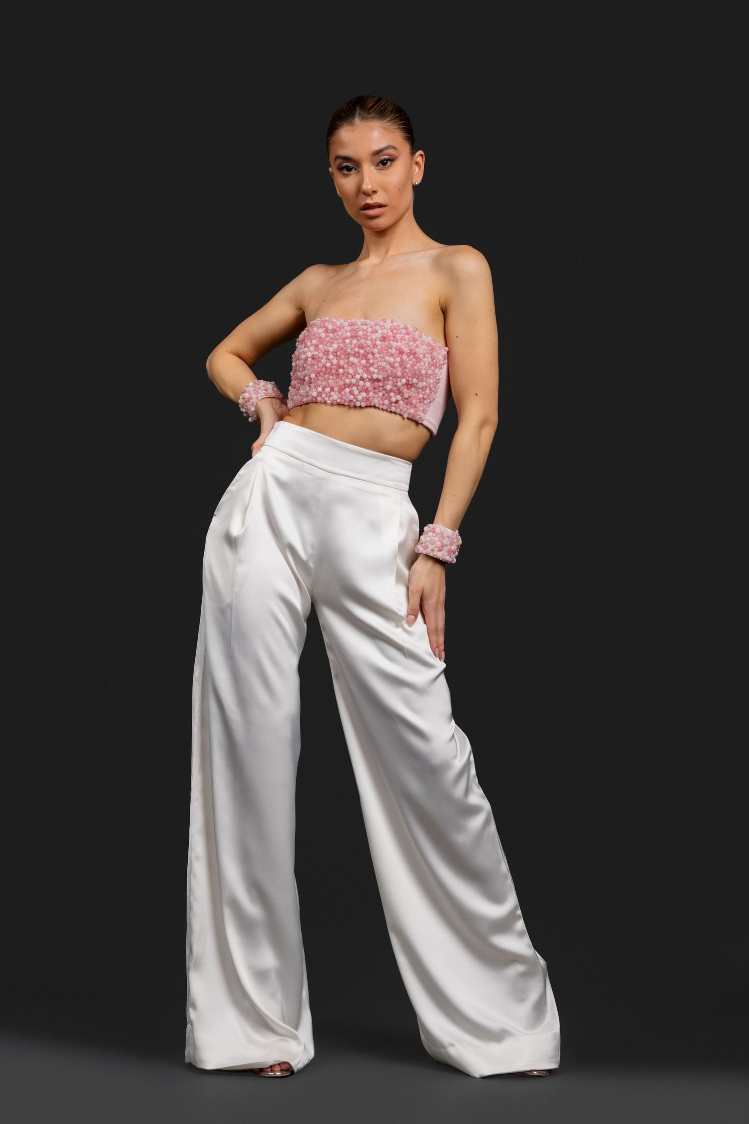 Model wearing a pink floral strapless crop top with white satin wide-leg trousers and matching floral cuffs.