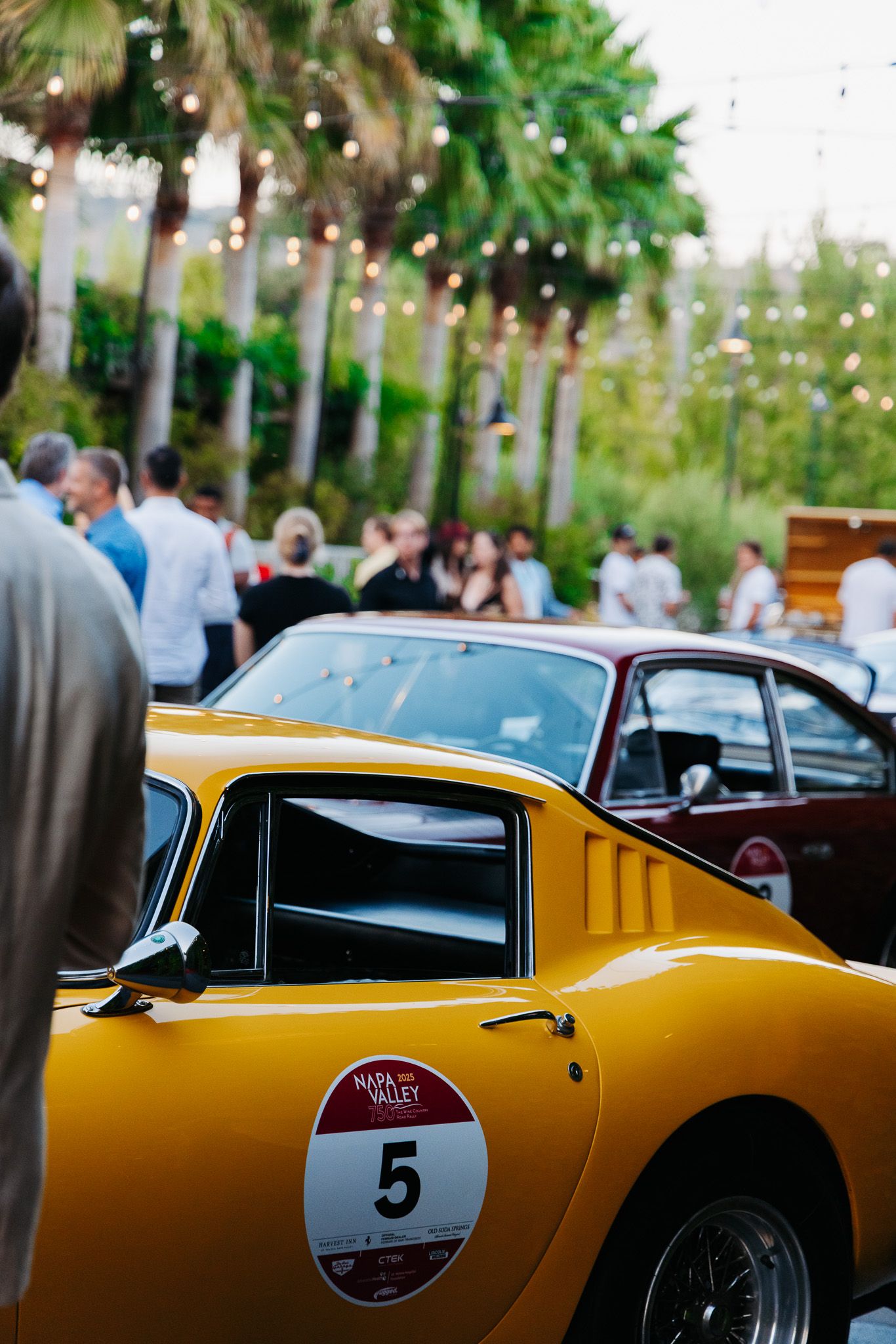 Yellow vintage sports car with racing number 9 displayed at an outdoor classic car event.