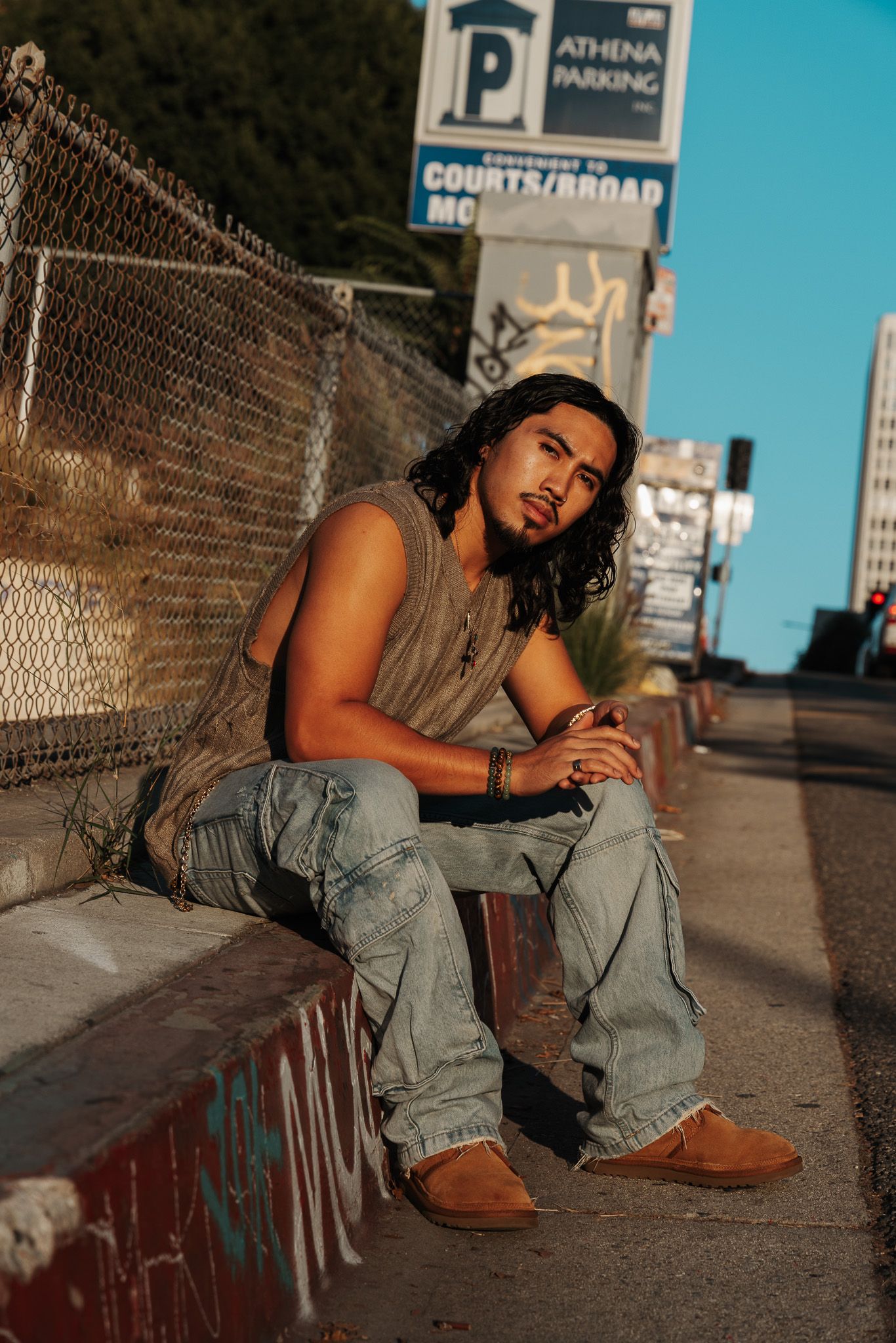 A series of casual outdoor portraits showing someone in overalls posing near a chain link fence at dusk.