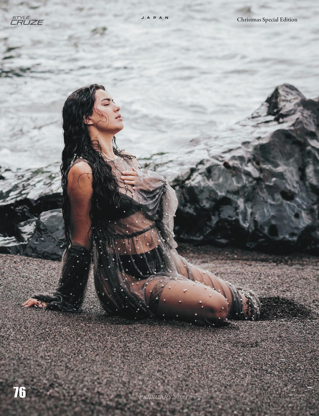 Dramatic beach photoshoot of model posing on rocky shore with waves in background.