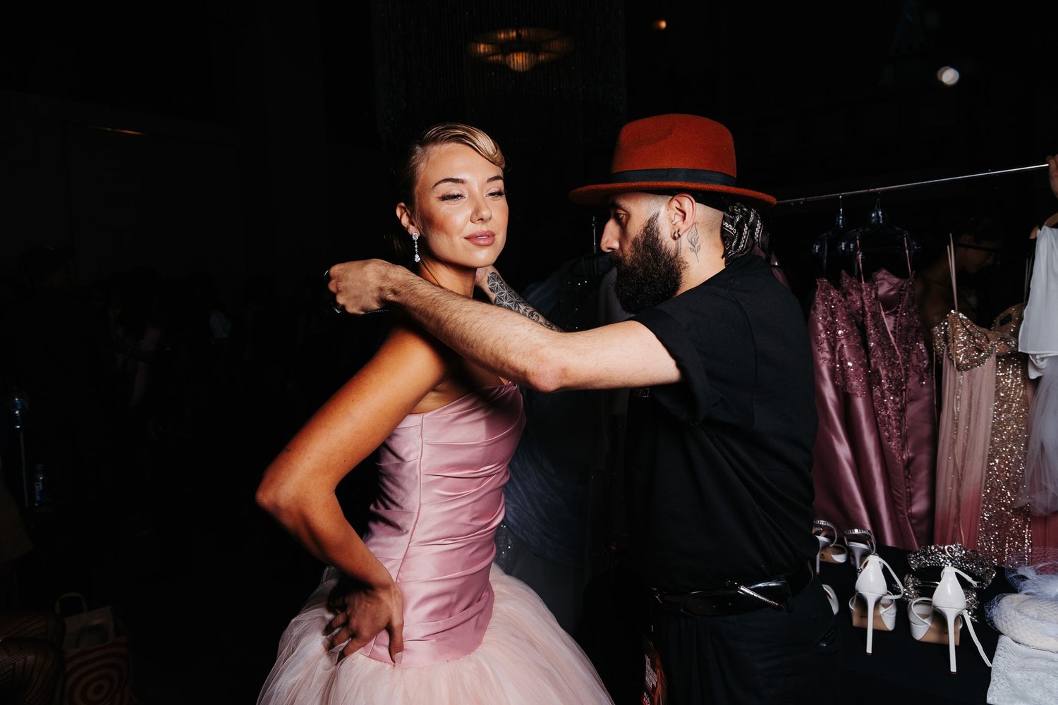 Dancers in formal attire perform elegant ballroom dance moves under dramatic lighting.
