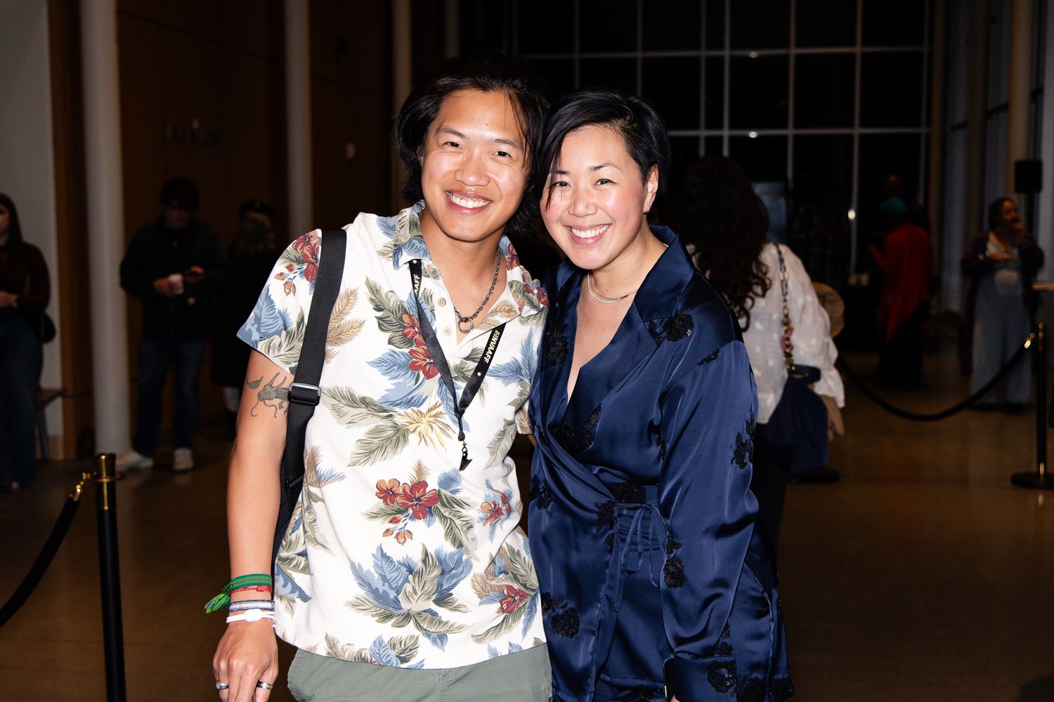 Two attendees at an evening event wearing casual and formal attire.