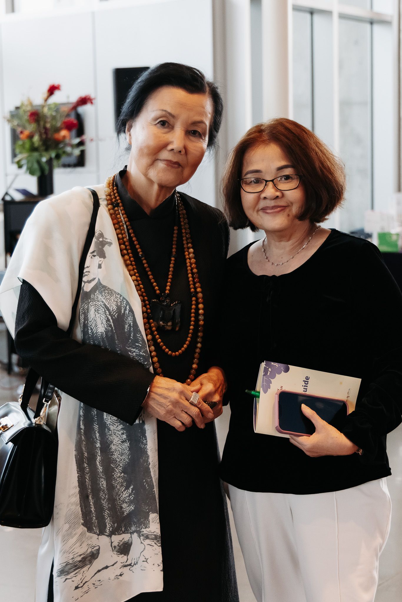 Two people in black and white outfits exchanging gifts at a formal event.