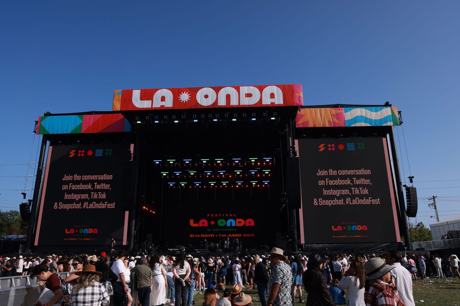 Festival attendees gather in front of the La Onda stage with large LED screens and red branding at an outdoor music event.