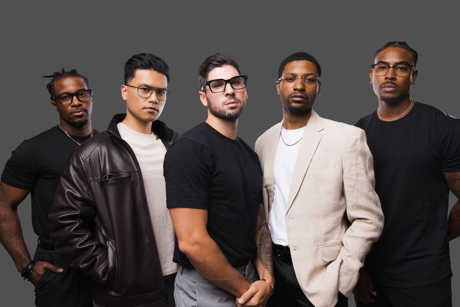 Five stylish men posing together against a gray background in a professional group portrait photo.