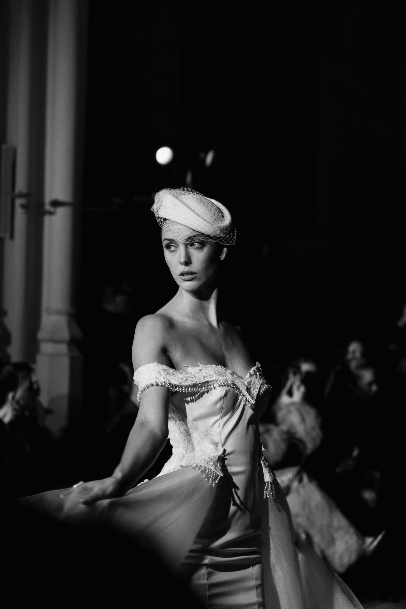 A series of black and white fashion photographs showing a model in an elegant off-shoulder dress and white headpiece.