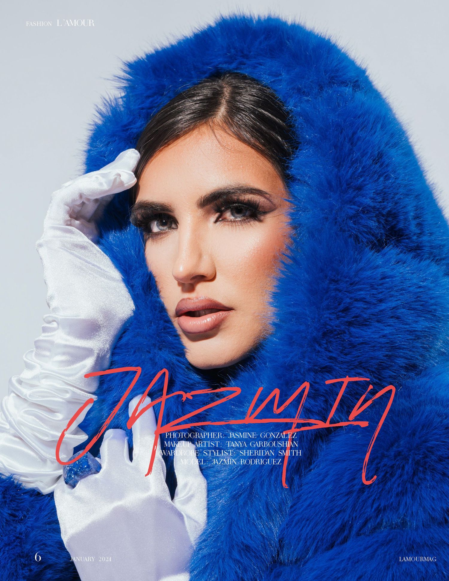 Beauty portrait featuring bright blue fur hood and white gloves against grey background.