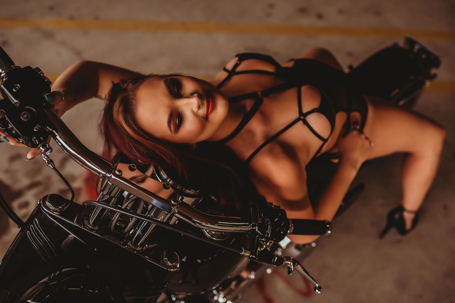 Intimate boudoir session with vintage motorcycle prop and dramatic lighting.