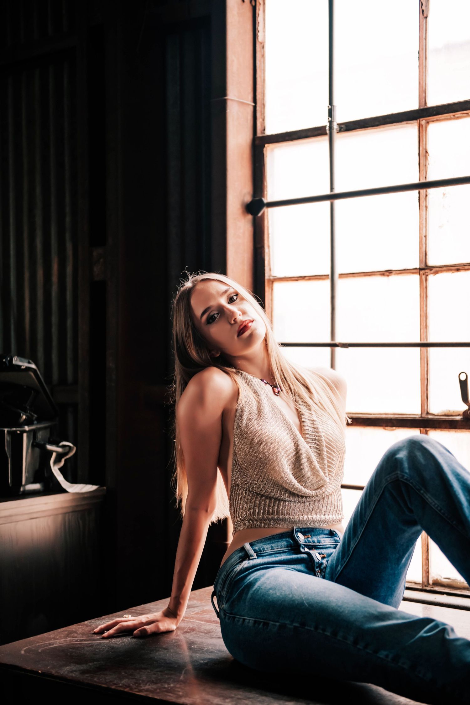 Fashion portrait near window with natural light, showing casual crop top and jeans.